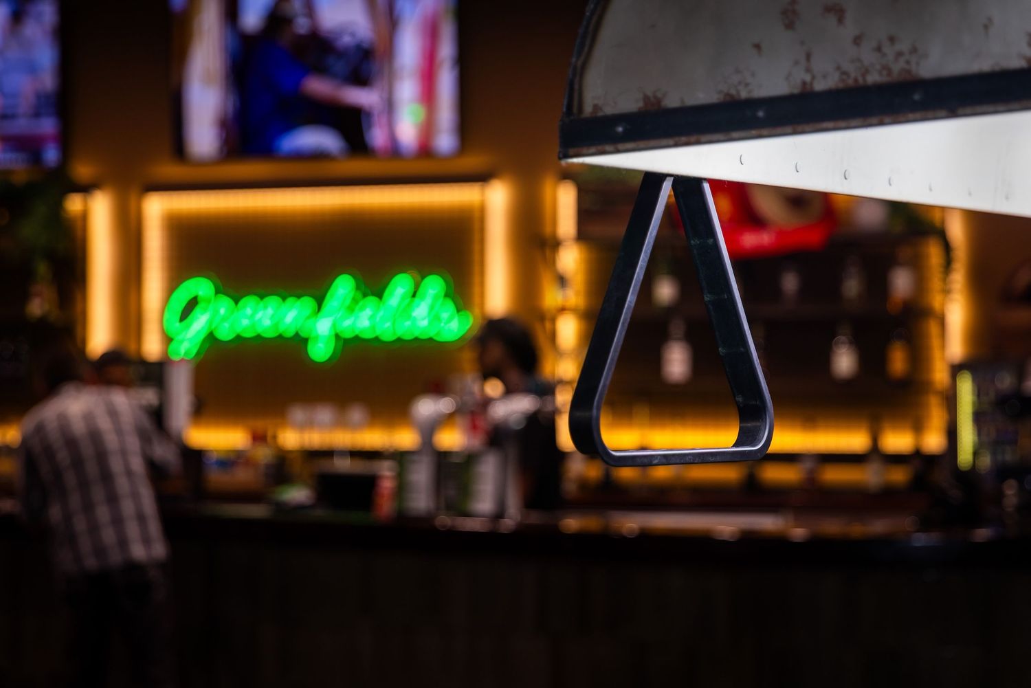 Illuminated bar interior with glowing neon signs and warm ambient lighting creating a cozy nightlife atmosphere.