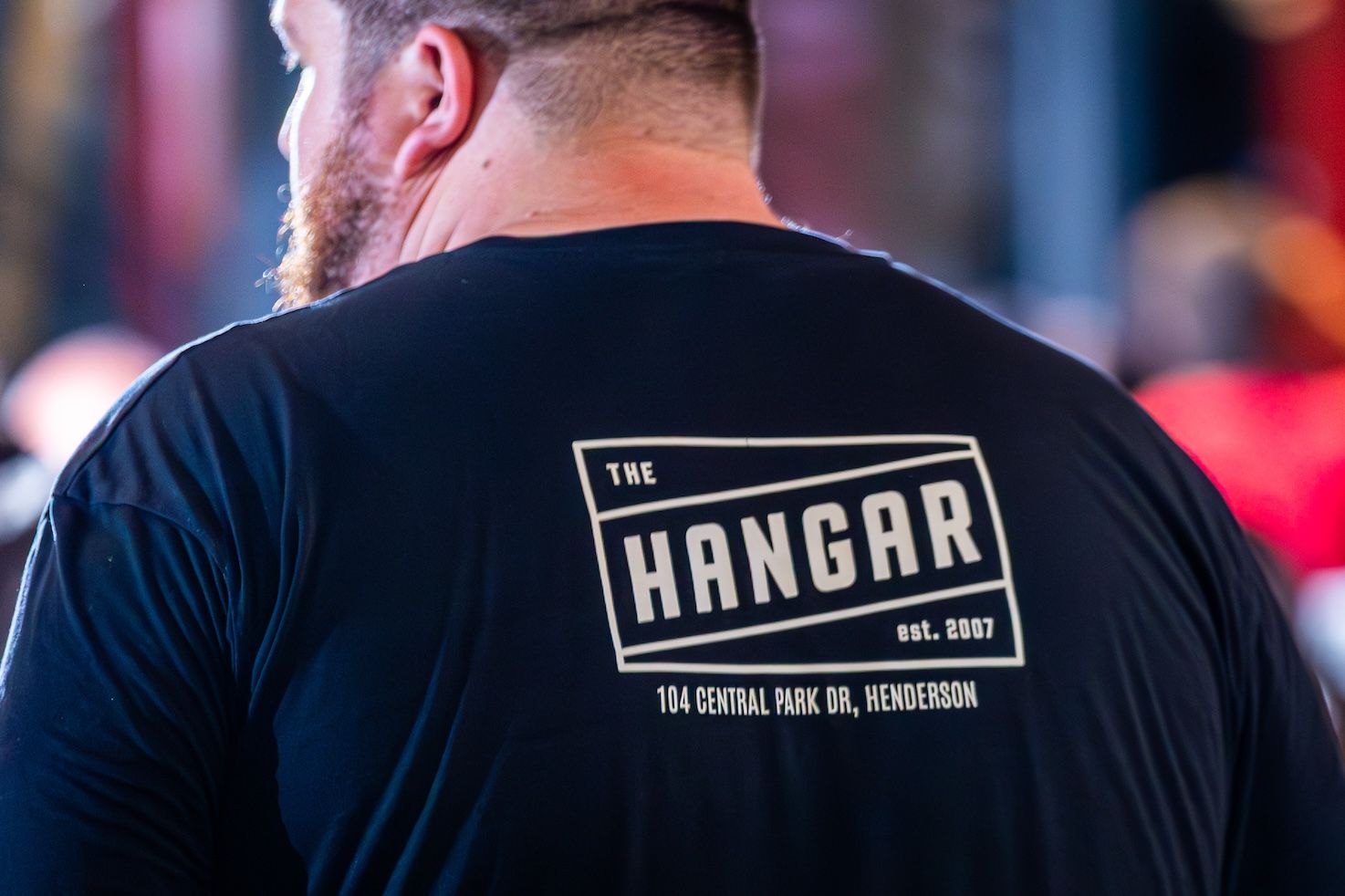 A black t-shirt with white text design is displayed against a red background.