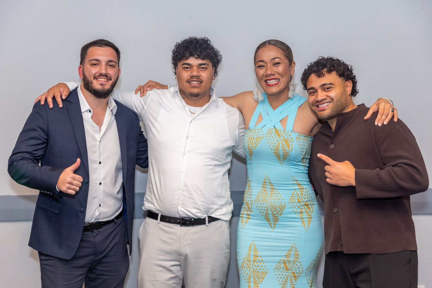 Four young adults smiling and posing together at a formal event, dressed in elegant attire.