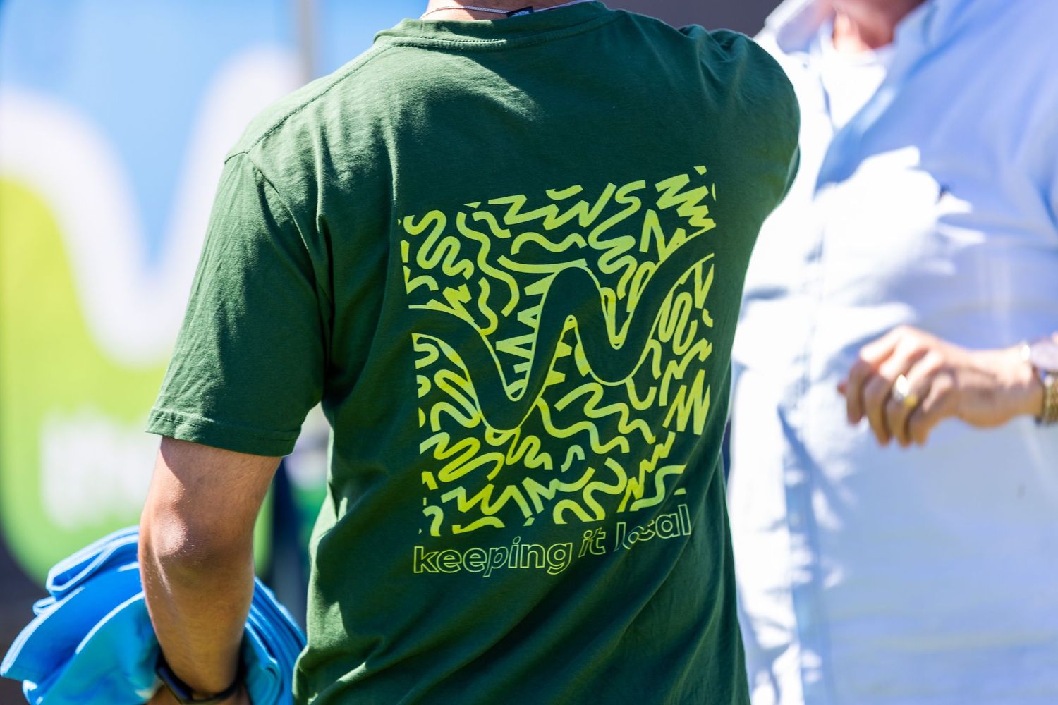 Close-up of green t-shirts with neon yellow geometric patterns and text.