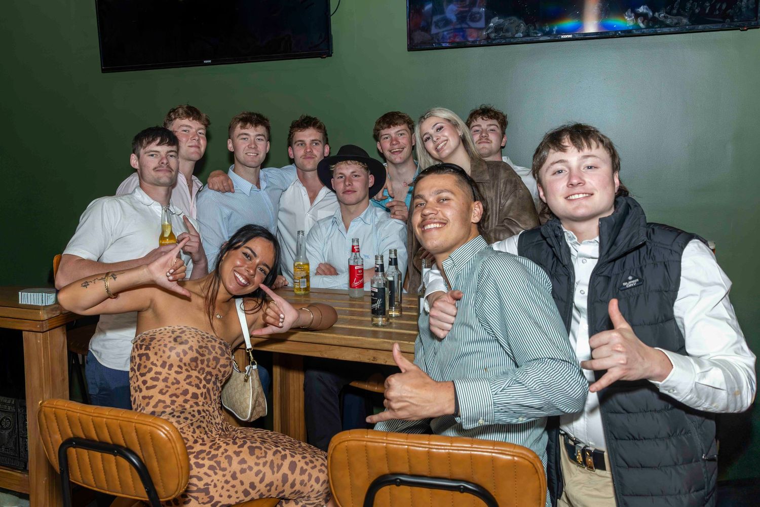Group of young adults smiling and posing together inside a bar or venue.