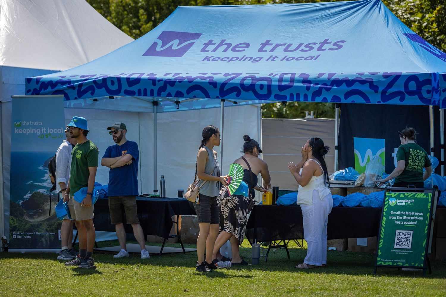 Row of white promotional tents with blue accents set up at an outdoor community event.