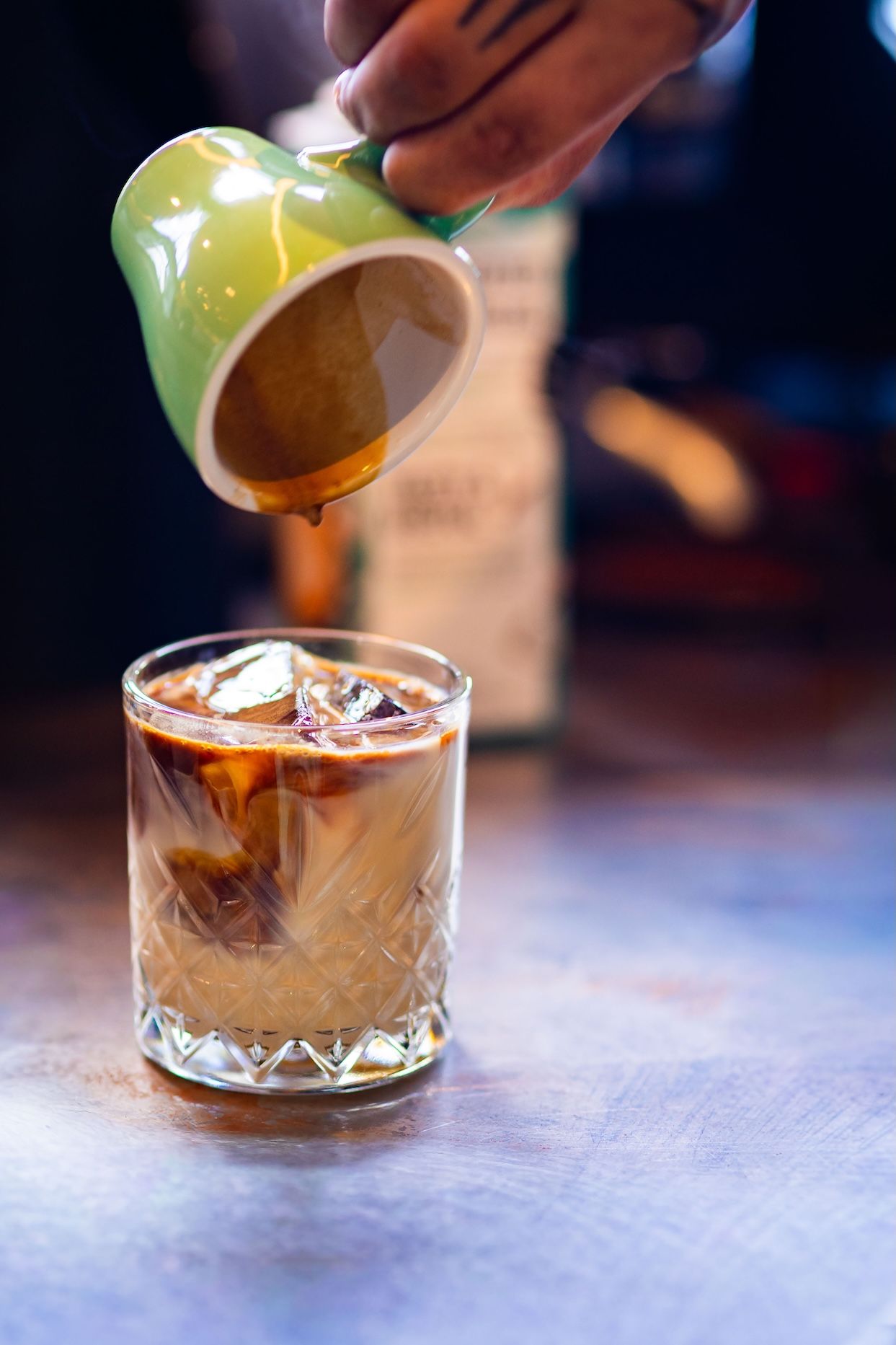 A series of photos showing a cocktail being poured into a crystal glass with ice cubes.