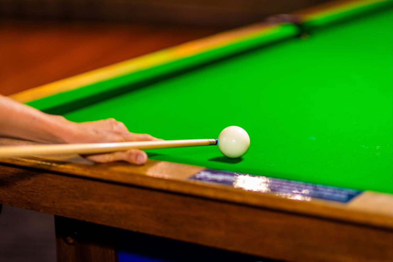 A close-up sequence of a snooker player hitting a white cue ball on a green felt table during a game.