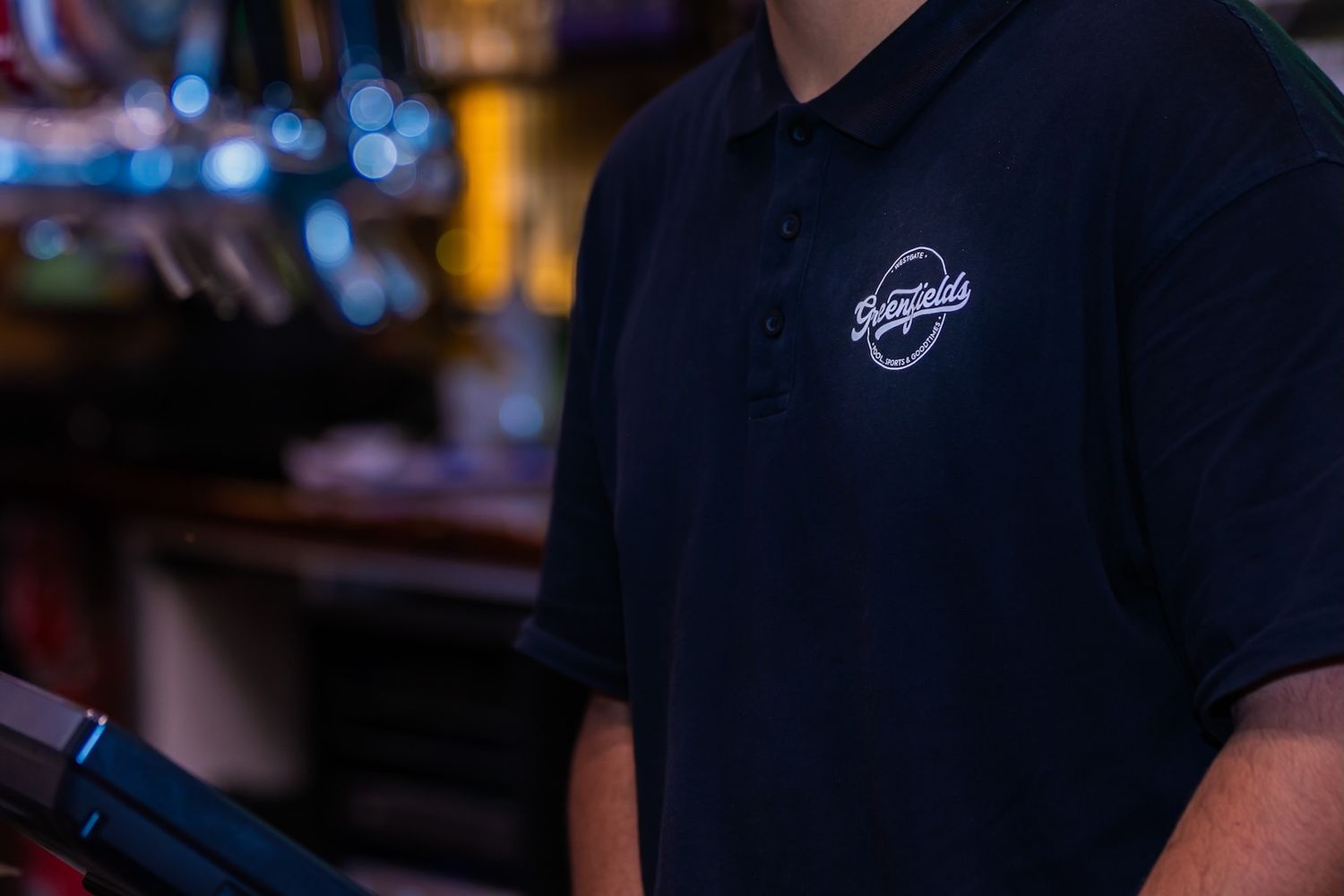 Close-up shot of draft beer taps in a dimly lit bar setting with bokeh lights in the background.
