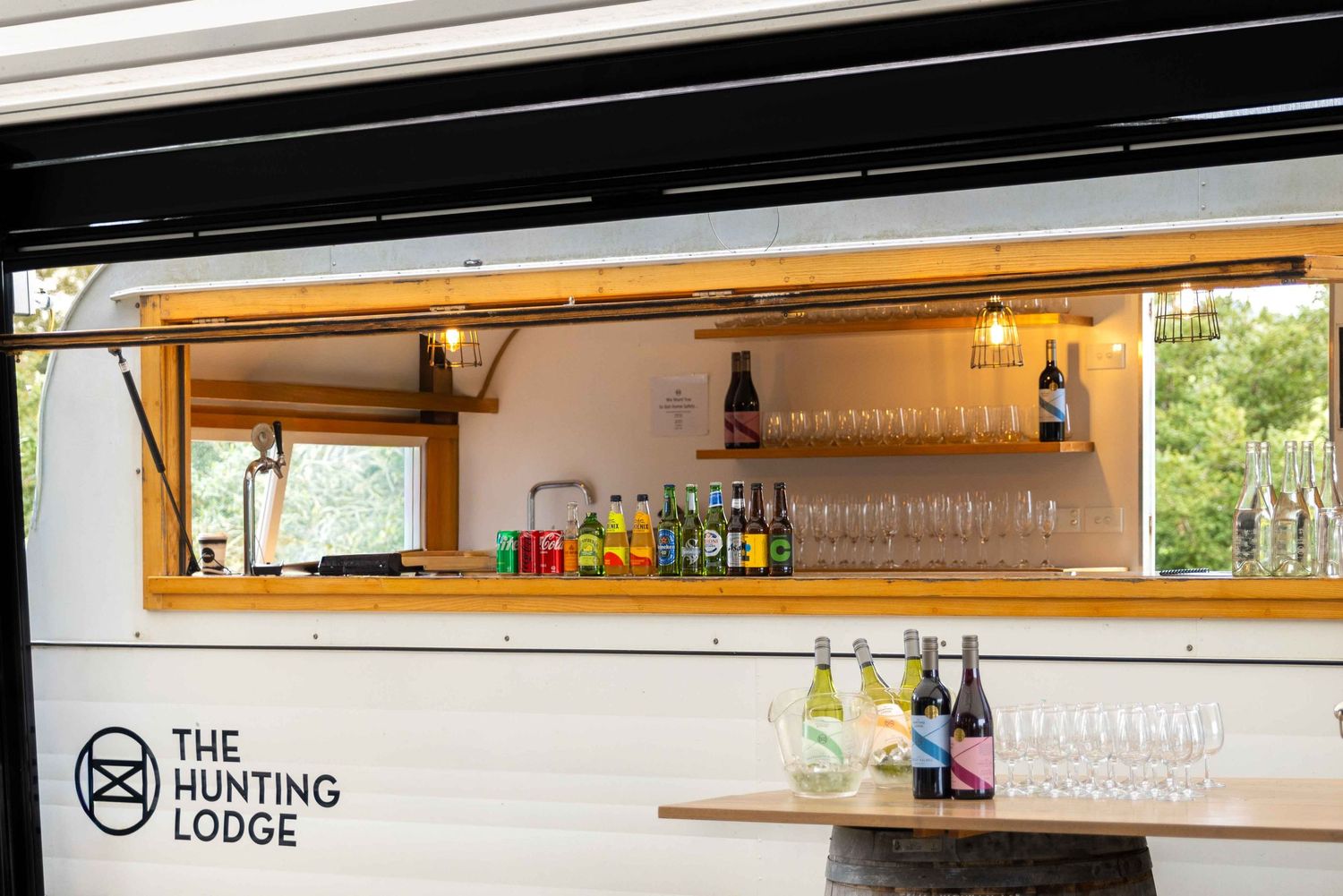 The Hunting Lodge mobile bar trailer with wine glasses, bottles, and tap system on display.