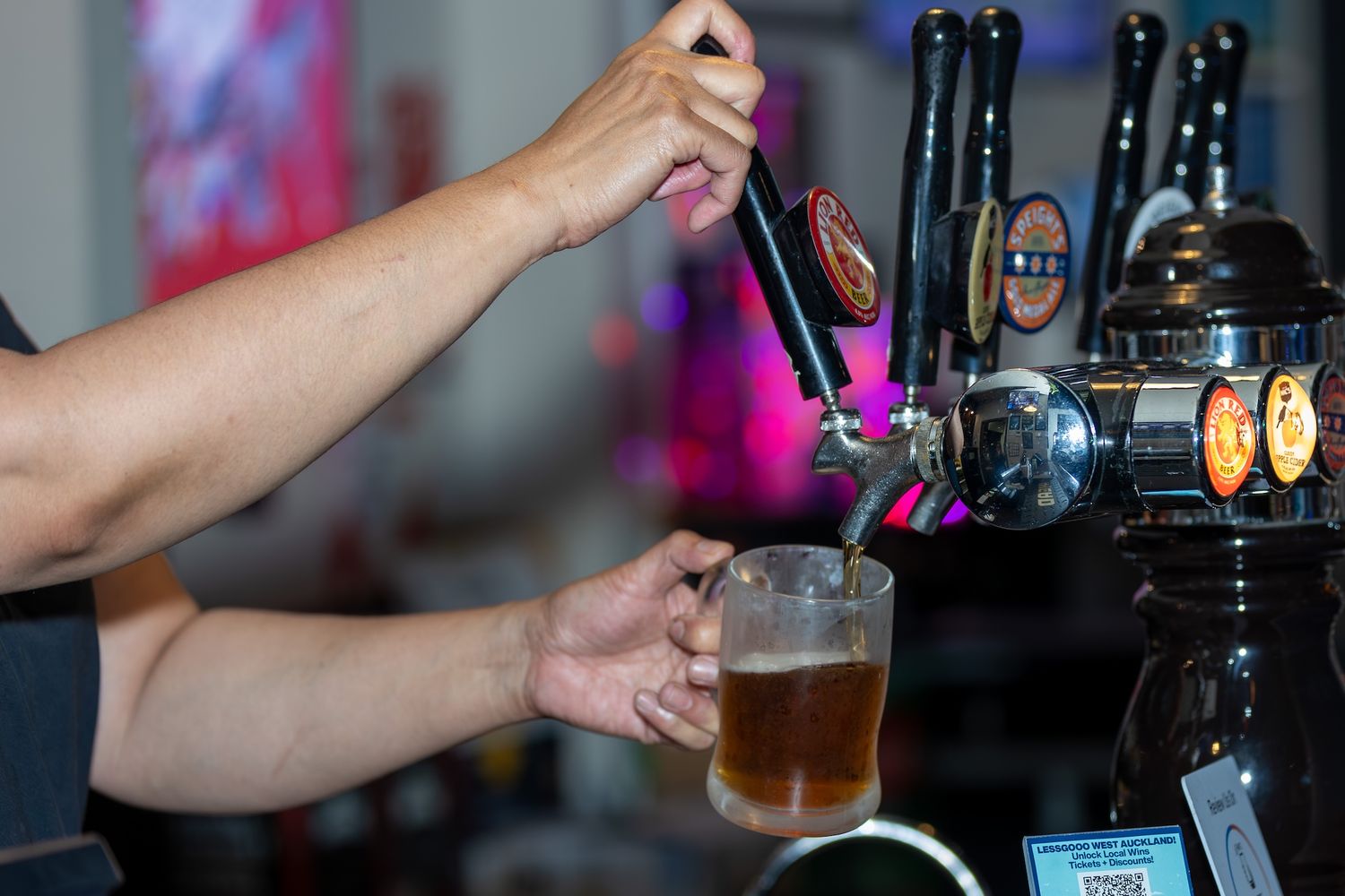 Beer taps at bar with glasses being filled from draft system.