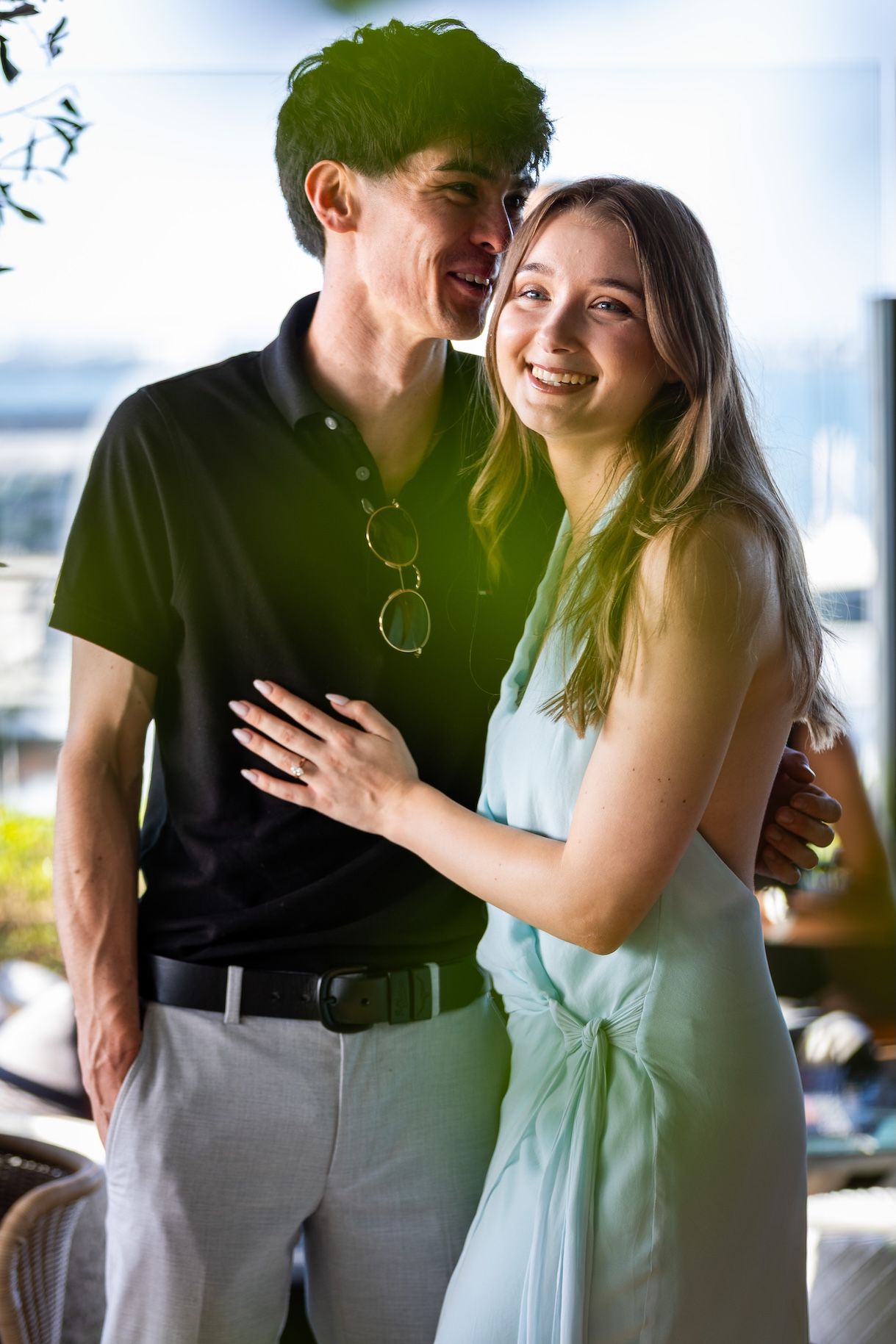 Happy young couple embracing and smiling together in a bright indoor setting, woman in mint dress.