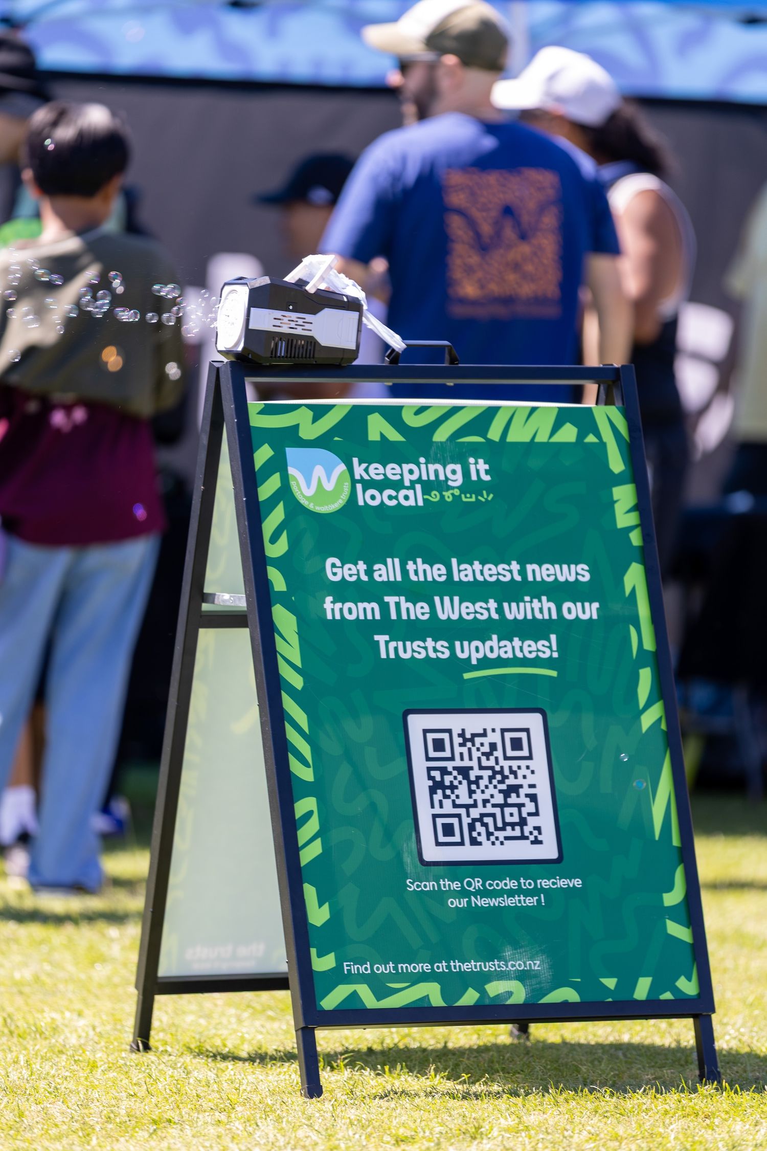 Green A-frame signs with QR codes displayed on grass at an outdoor event.