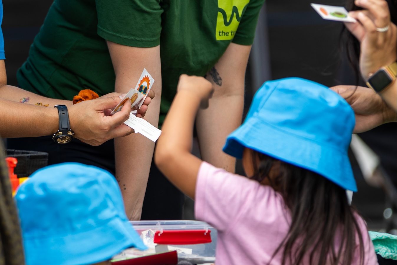 People holding promotional items at crowded outdoor event.