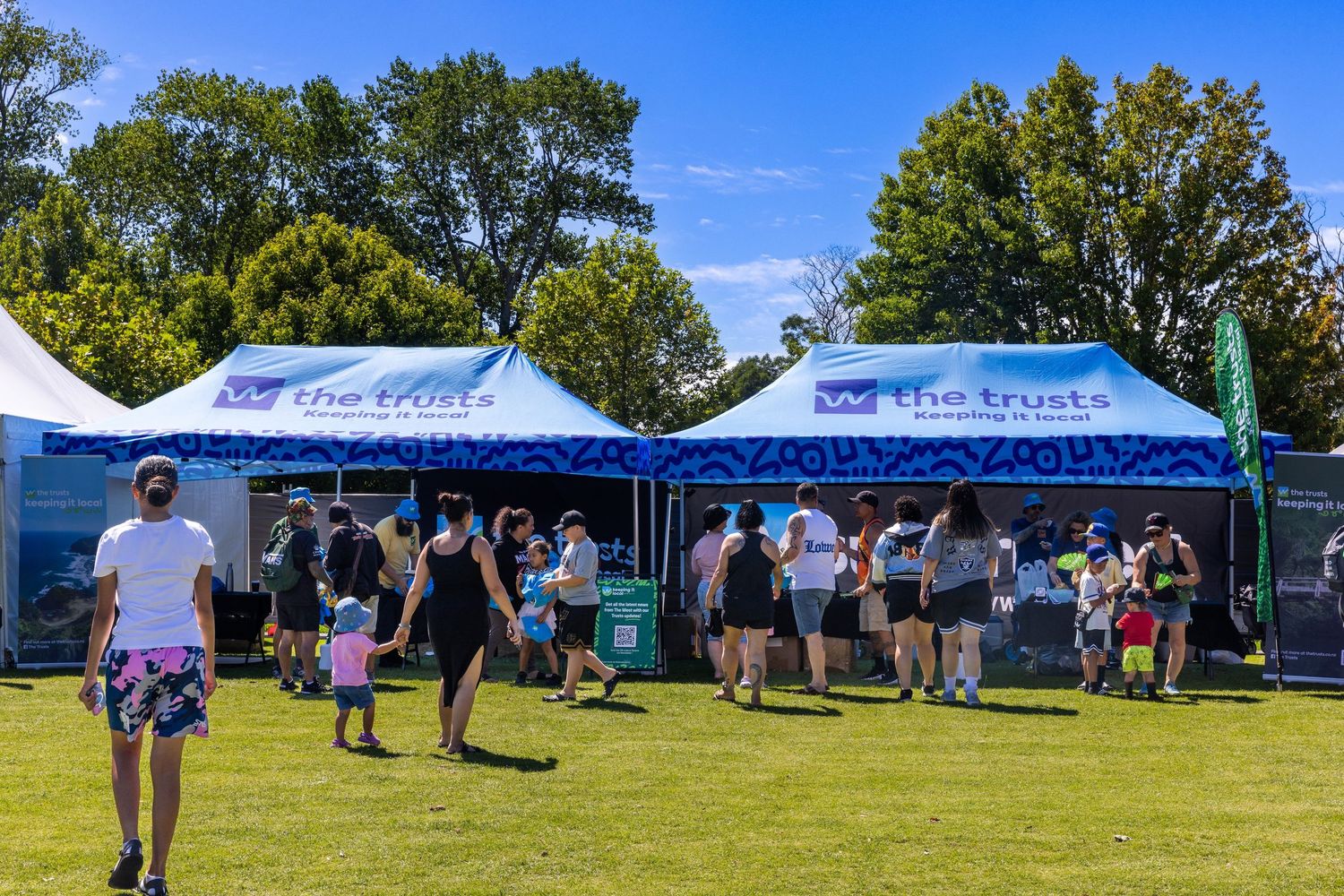 Event attendees browsing under promotional tents during sunny outdoor gathering.