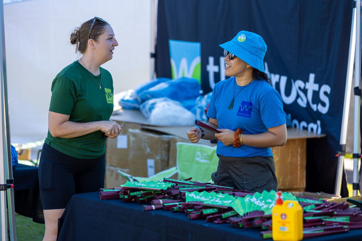 Staff members organizing merchandise and supplies at an event booth.