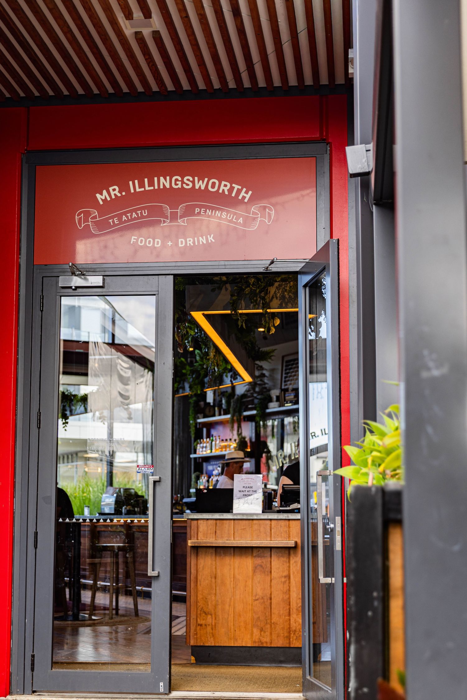 A storefront view of Mr. Illingsworth restaurant with red trim and glass windows showing the interior dining area.