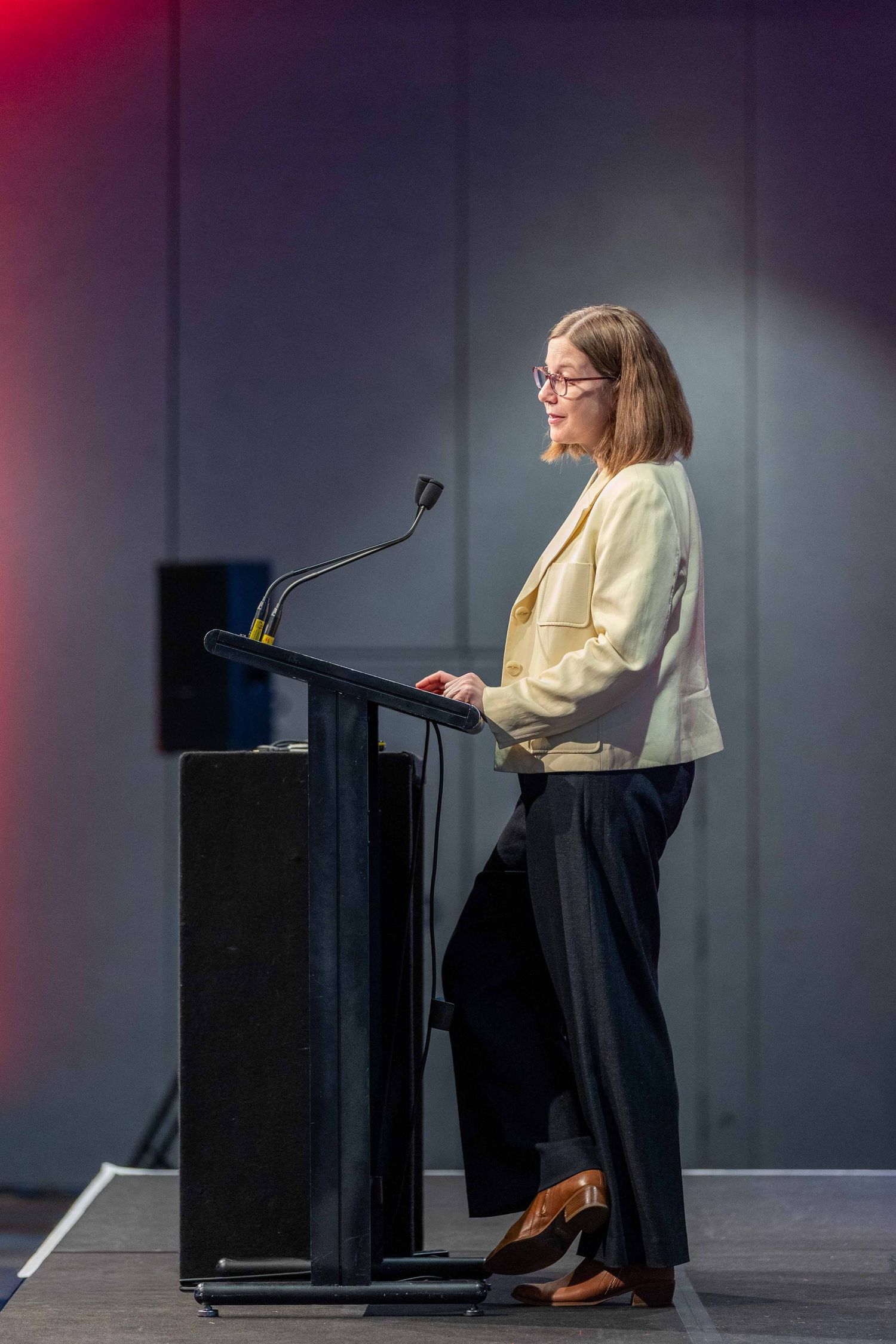 Side view of presenter speaking at black podium during corporate event.