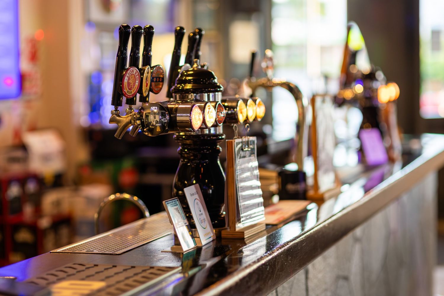 Close-up of bar counter showing assorted wine and liquor bottles with ambient lighting.