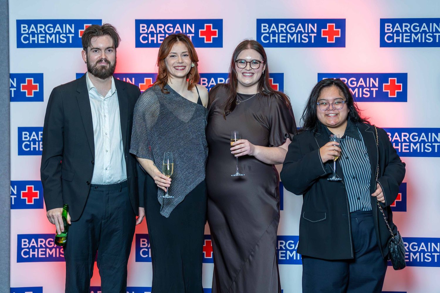 Group photo against branded step-and-repeat banner at corporate event.