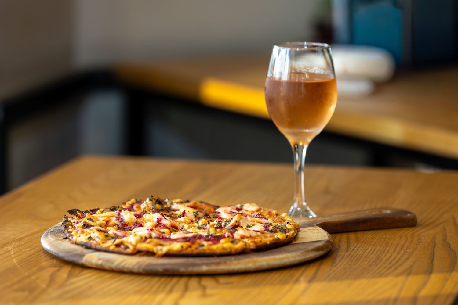 Restaurant table setting with golden wine glasses and pizza on wooden serving boards.