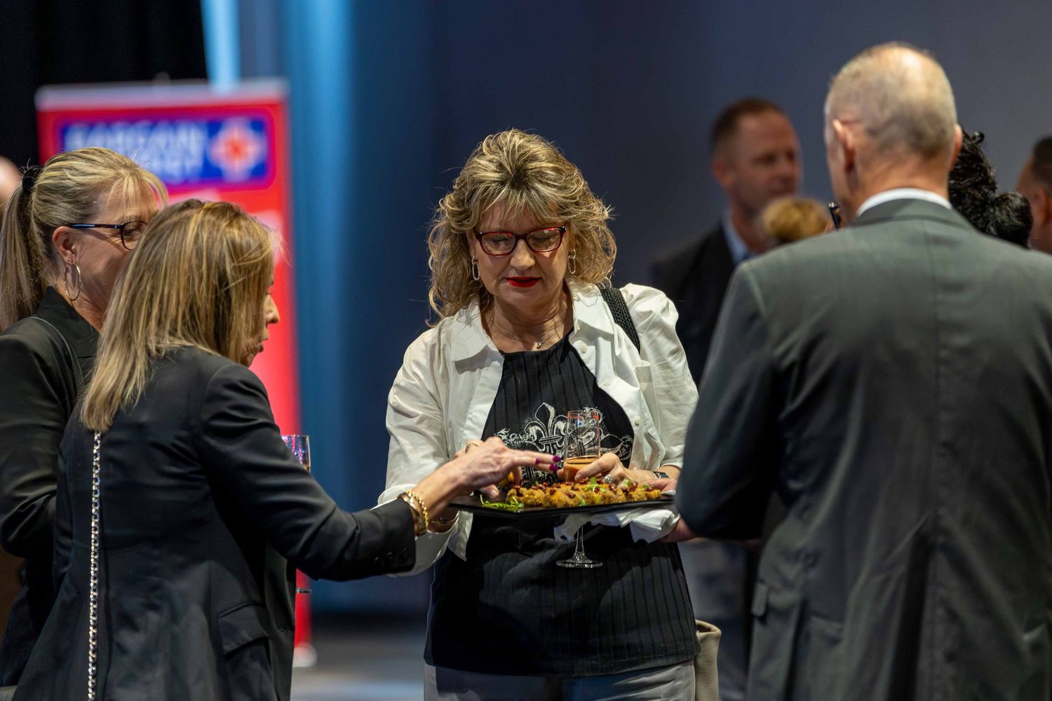 People mingling at a formal business event with drinks and refreshments.