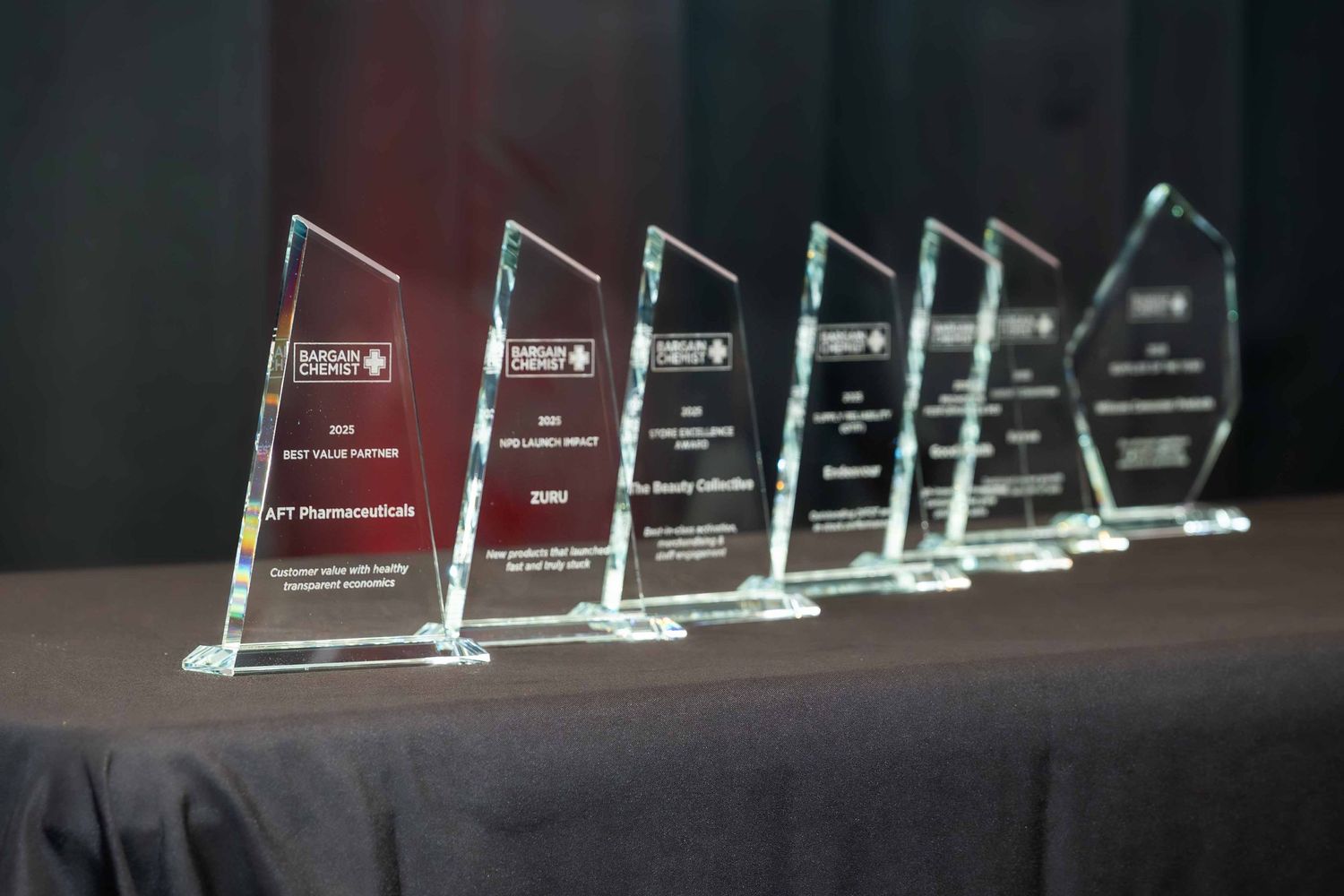 Row of clear glass or acrylic award trophies displayed on a dark surface.