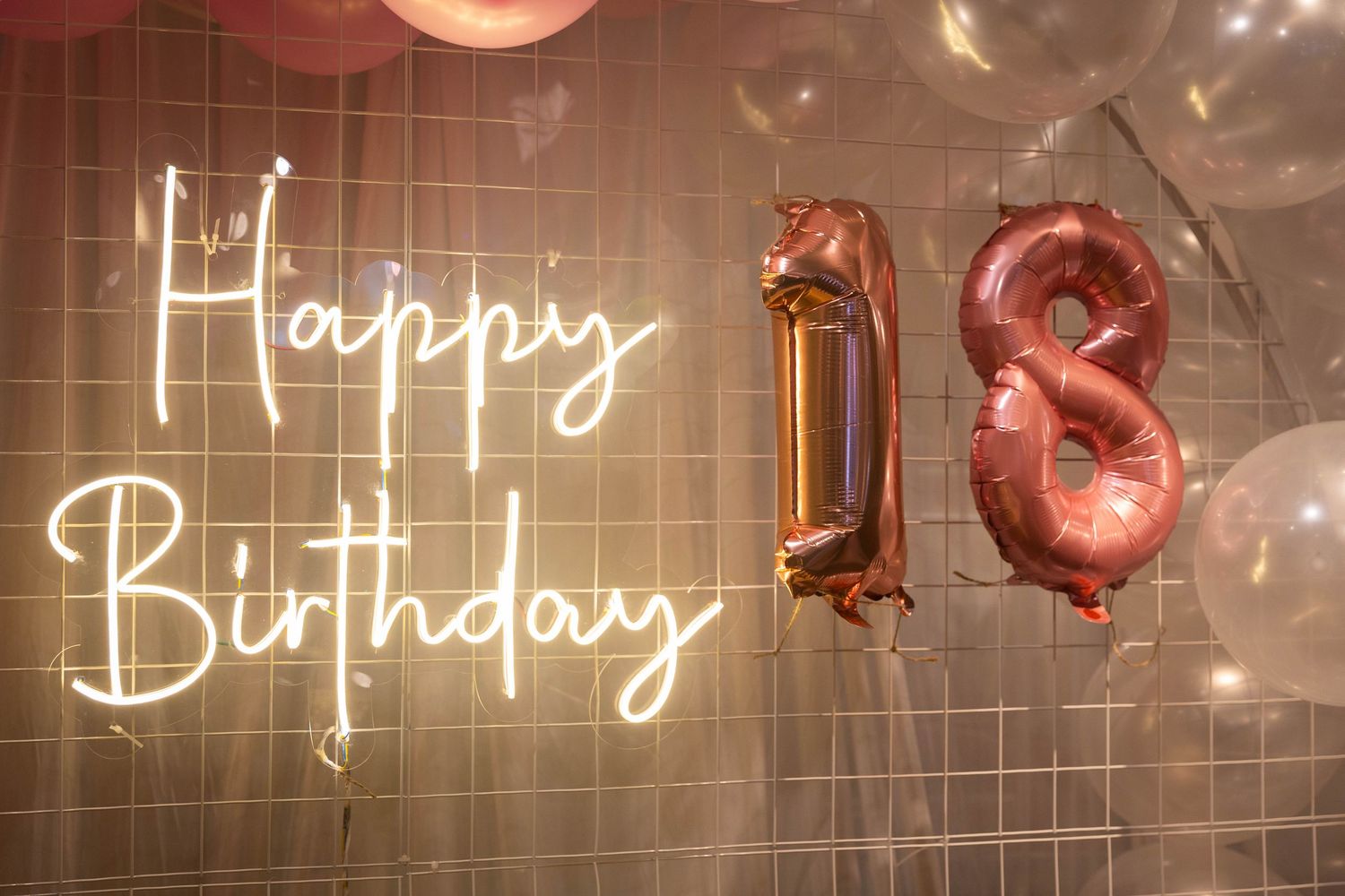 Neon Happy Birthday sign with rose gold number 18 foil balloons and pink balloons for an 18th birthday party.
