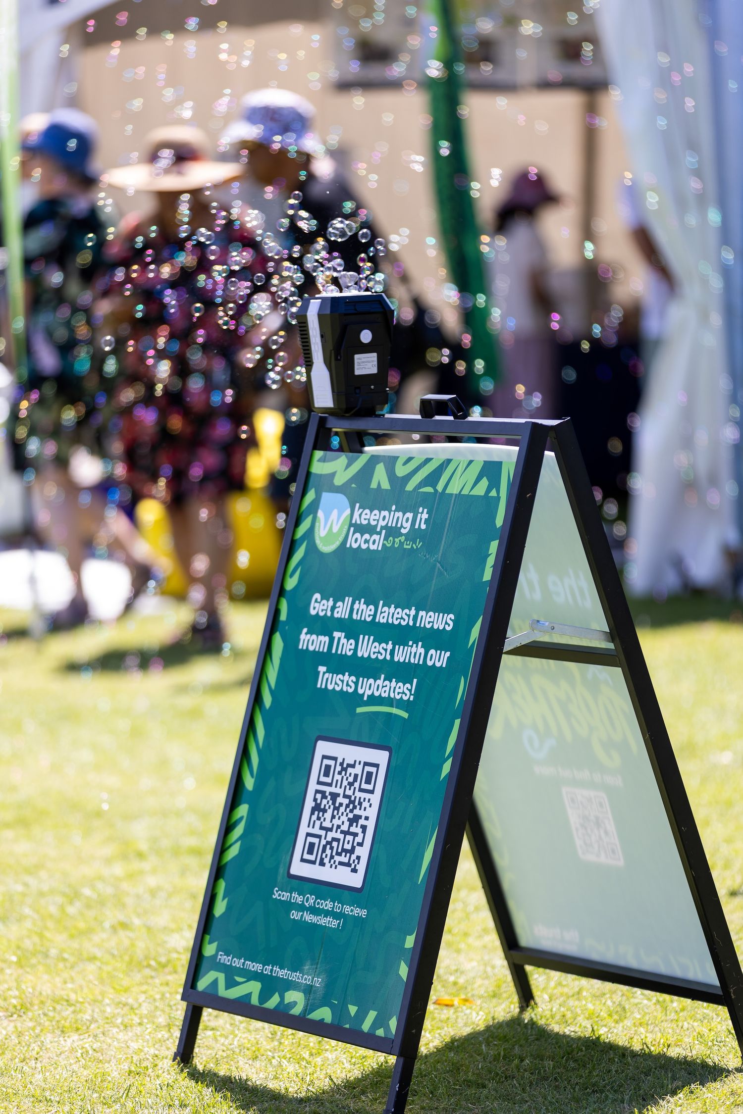 Green promotional signs with QR codes surrounded by floating bubbles in sunlight.