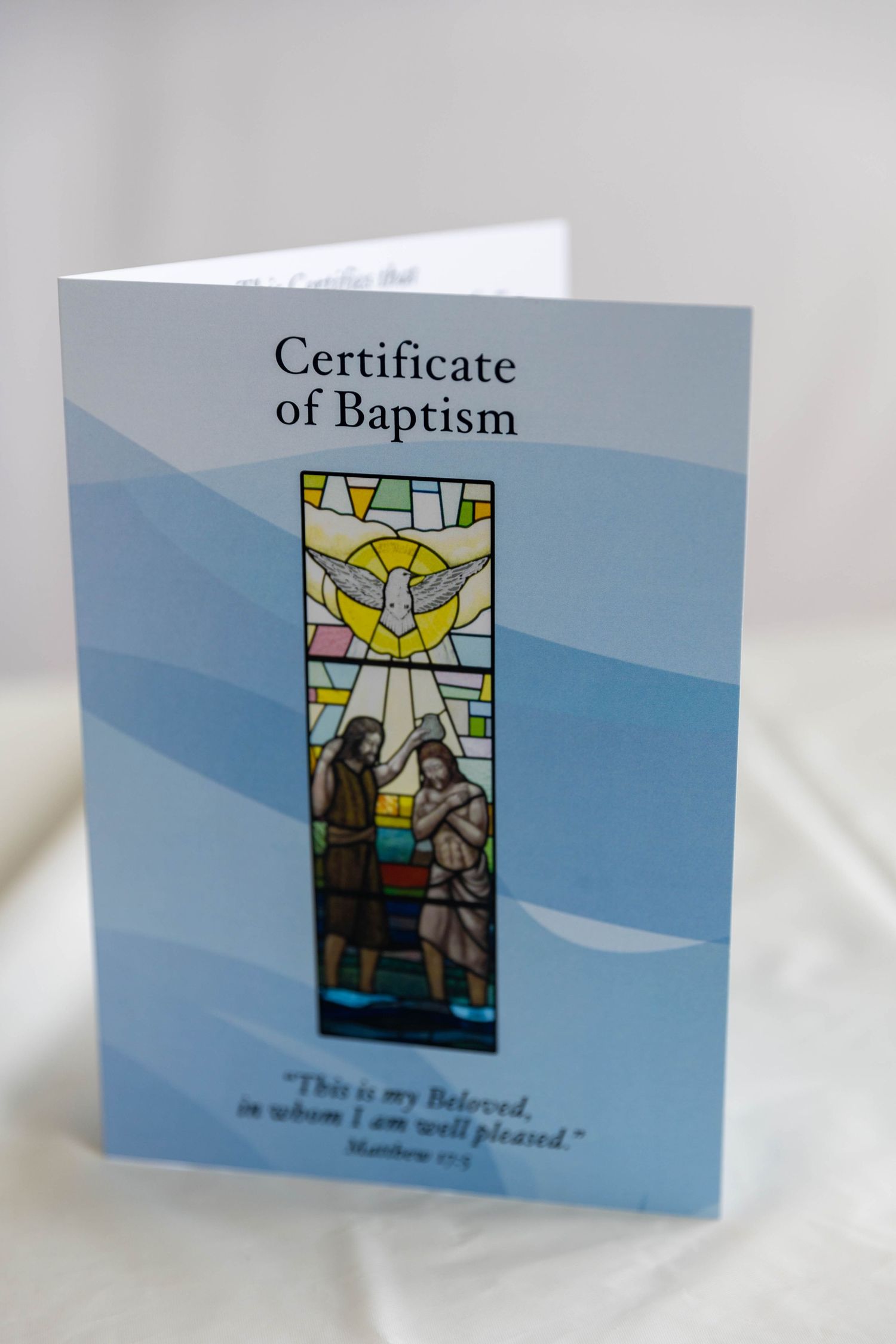 Certificate of Baptism card featuring stained glass artwork of baptism scene with Matthew 3:17 scripture quote.