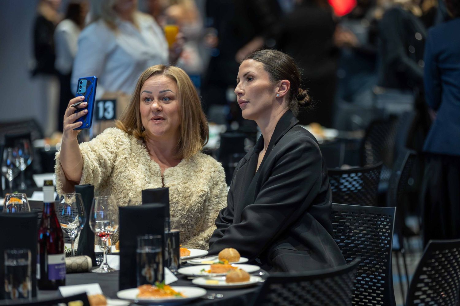 Attendees enjoying a formal dinner event in a dimly lit venue.
