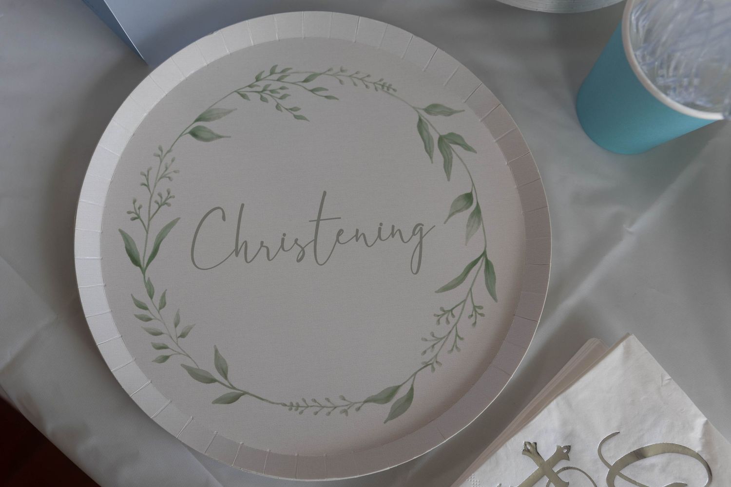 White Christening paper plate with green botanical wreath design, perfect for baptism party tableware.