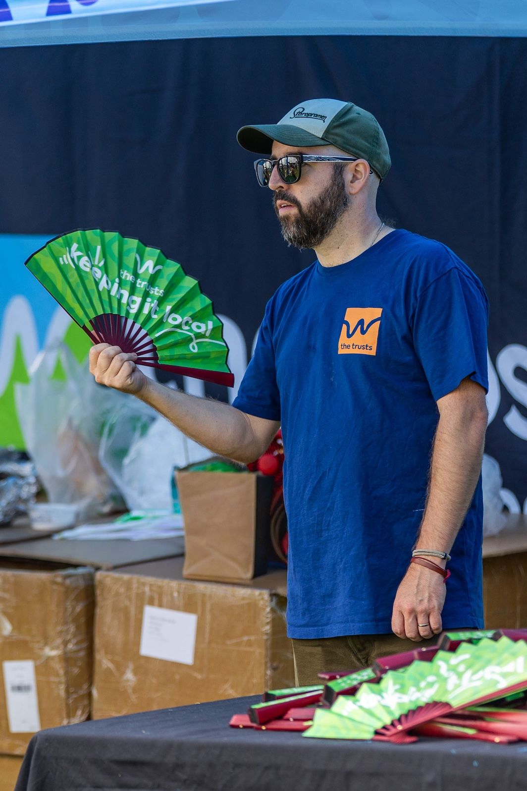 Staff members distributing green promotional items at outdoor event booth.
