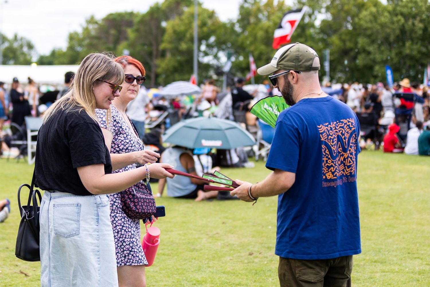 Attendees socializing at summer outdoor event with umbrellas and tents.