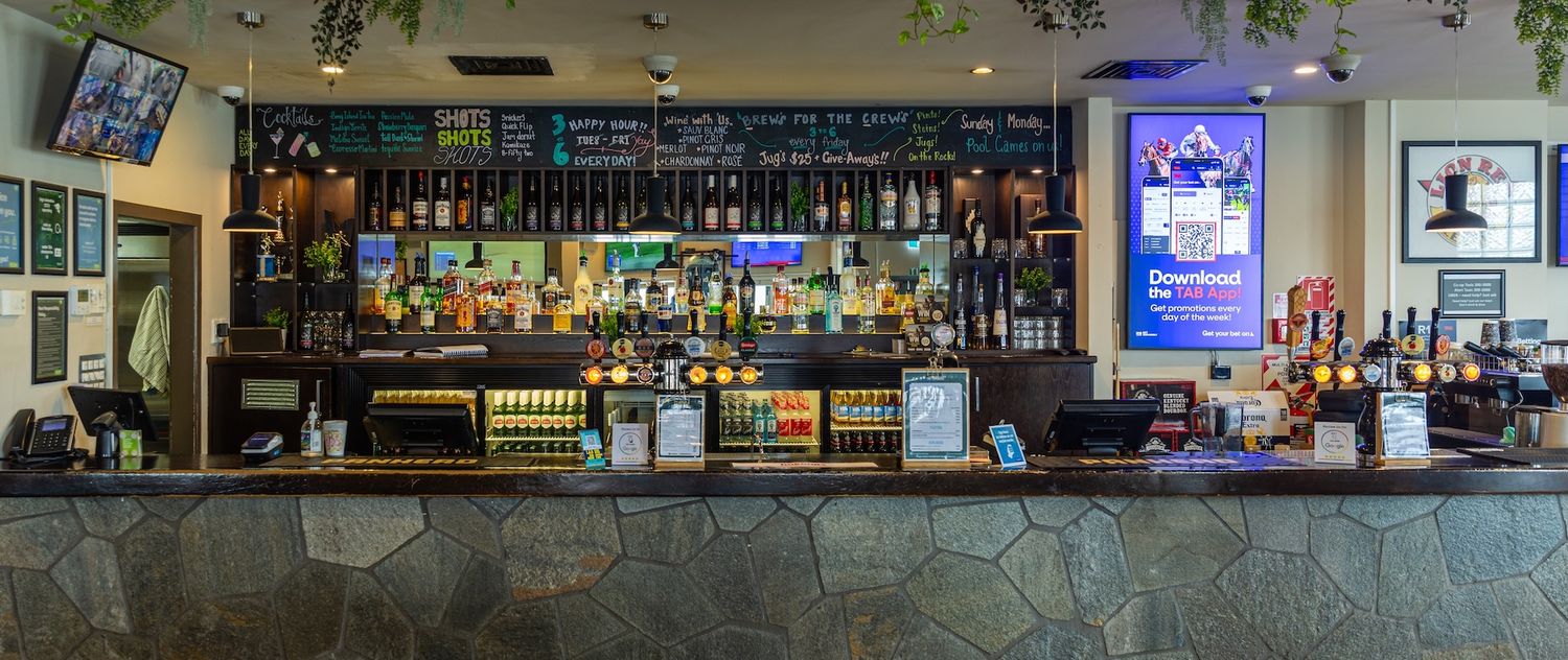Well-stocked bar shelves illuminated with blue lighting displaying numerous liquor bottles.