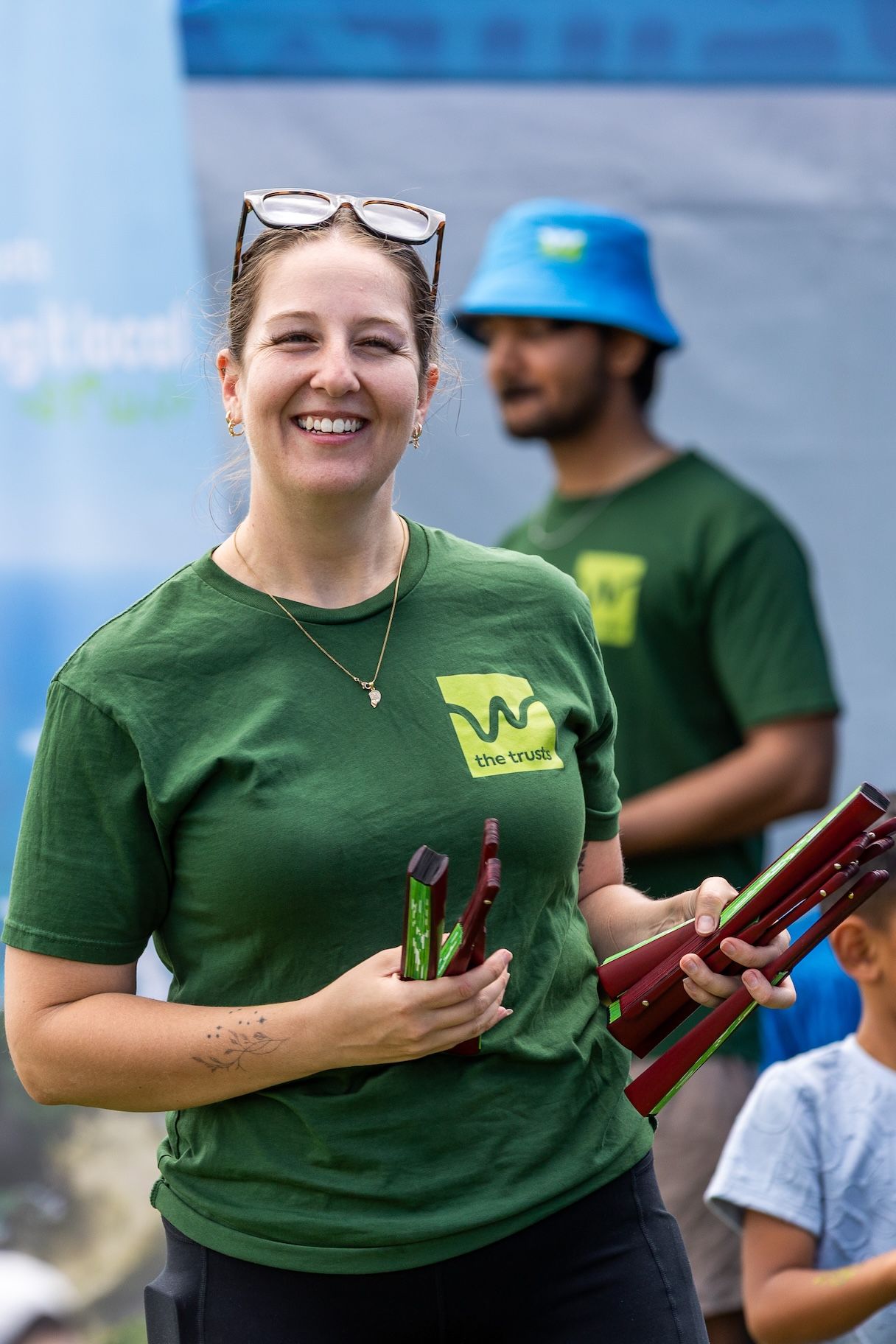 Staff members in green branded shirts handling promotional materials at outdoor event.