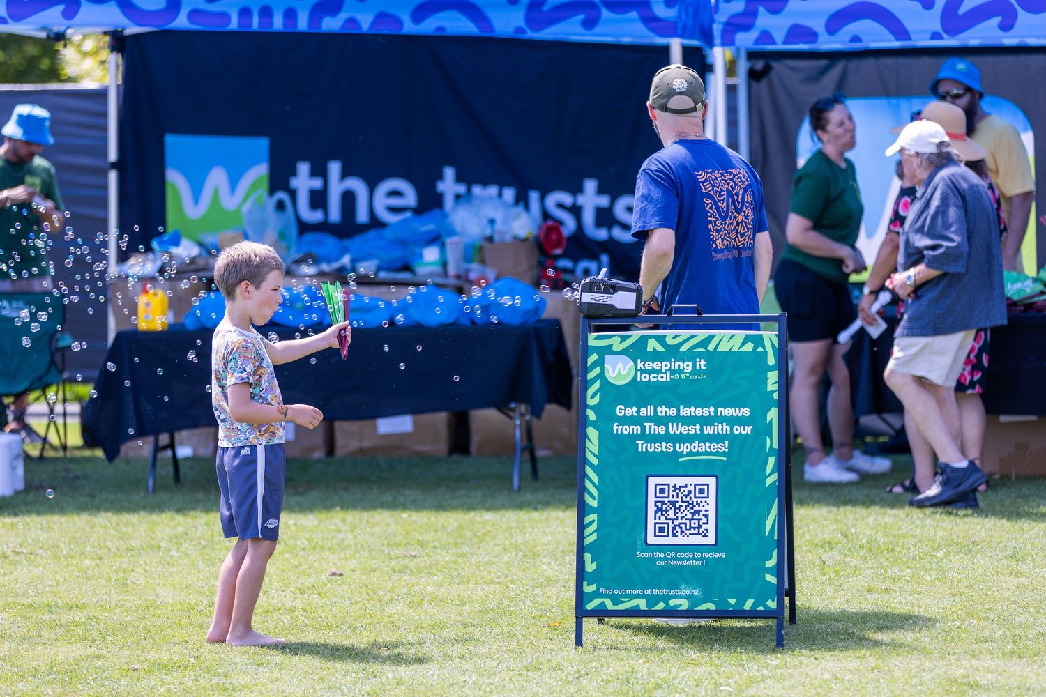 Green promotional banners and signage displayed on grass at outdoor community event.