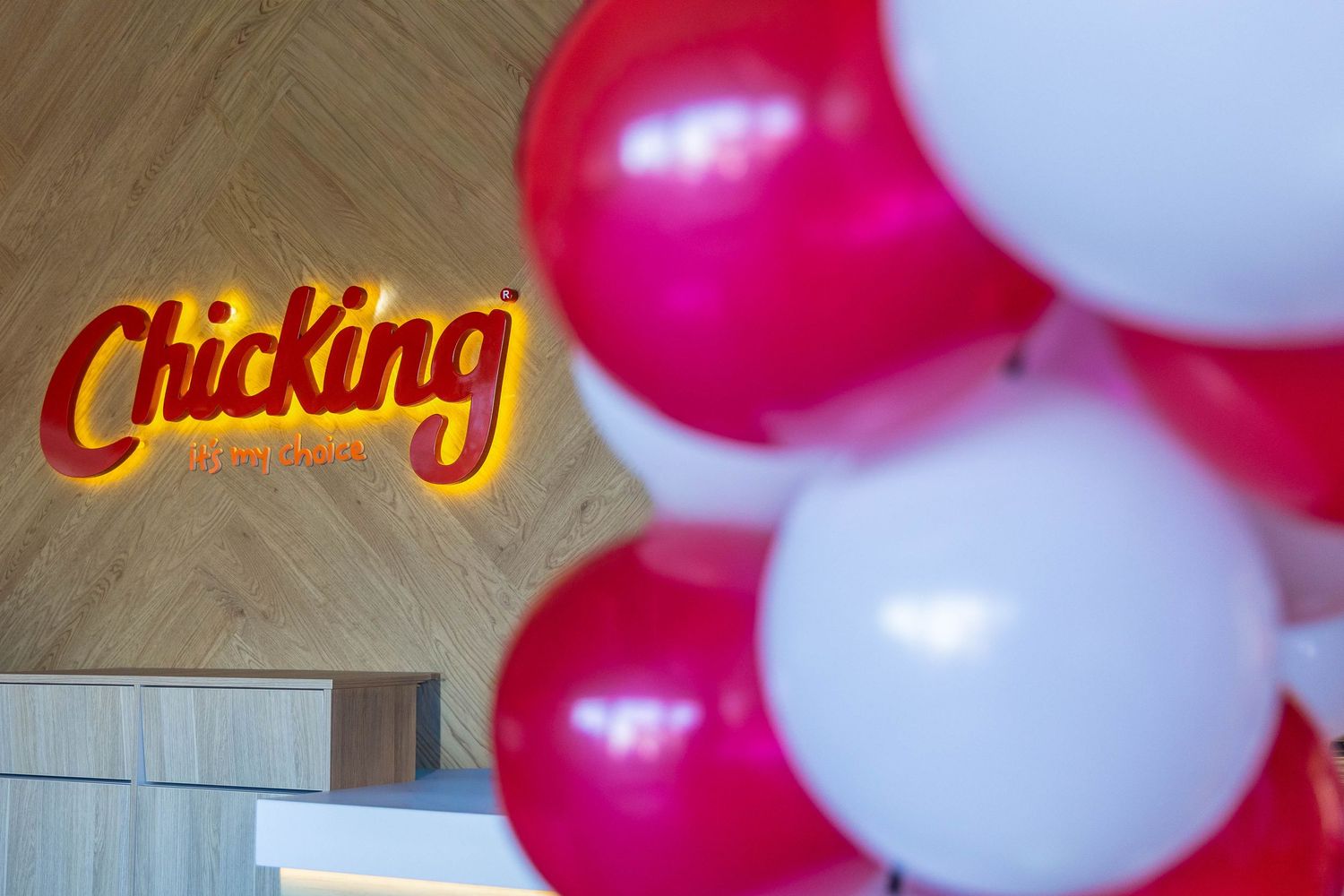 Chicking restaurant sign with red and white balloons during grand opening celebration.