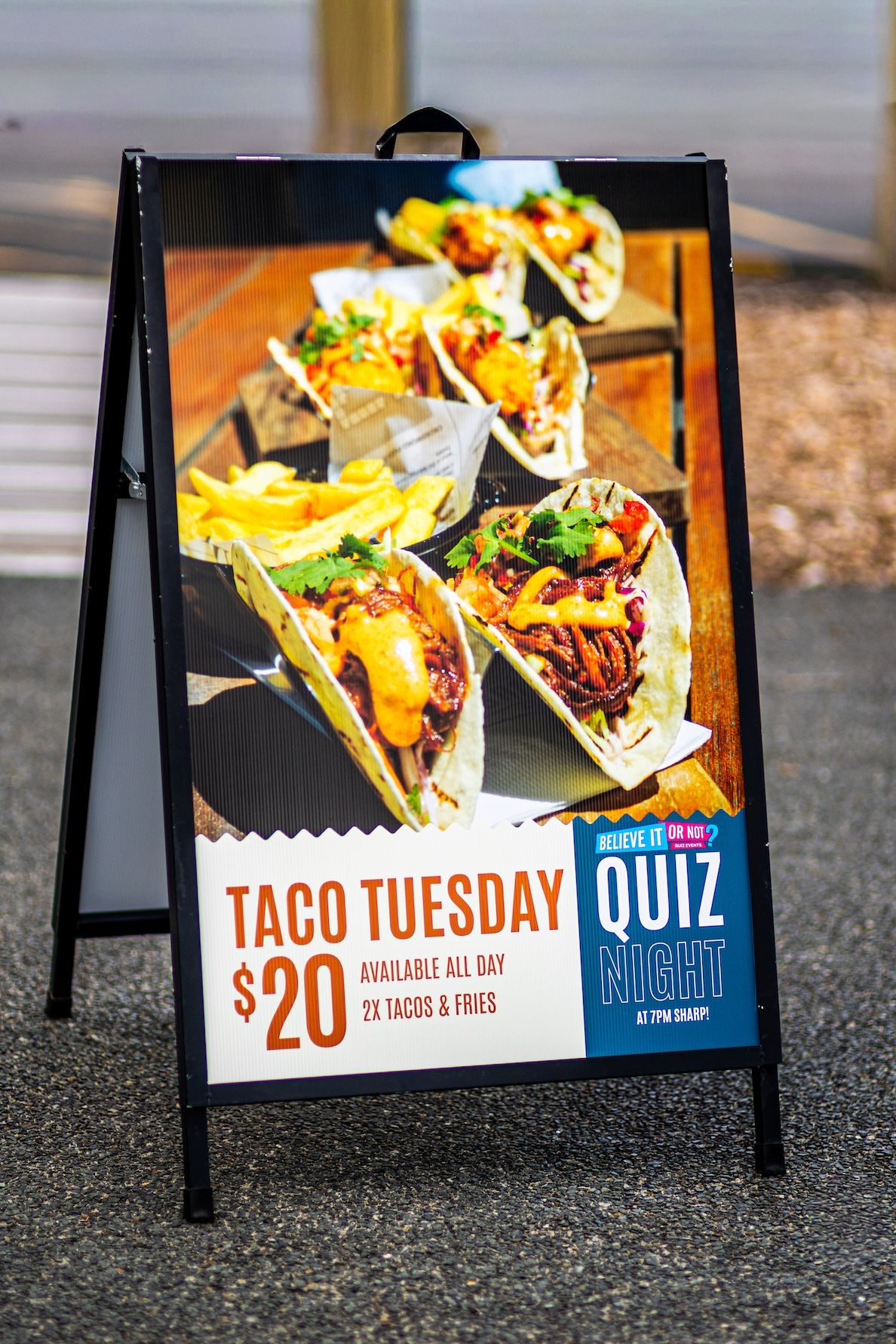 A series of sidewalk signs advertising Taco Tuesday specials with colorful photos of tacos and $20 deal promotions.