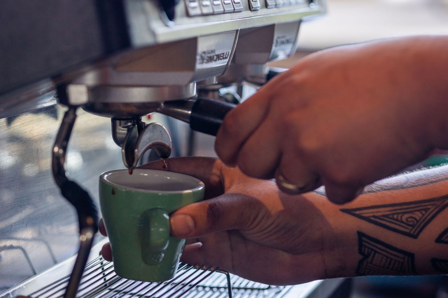 Hands preparing and pouring coffee at a professional coffee bar with various brewing equipment and tools.