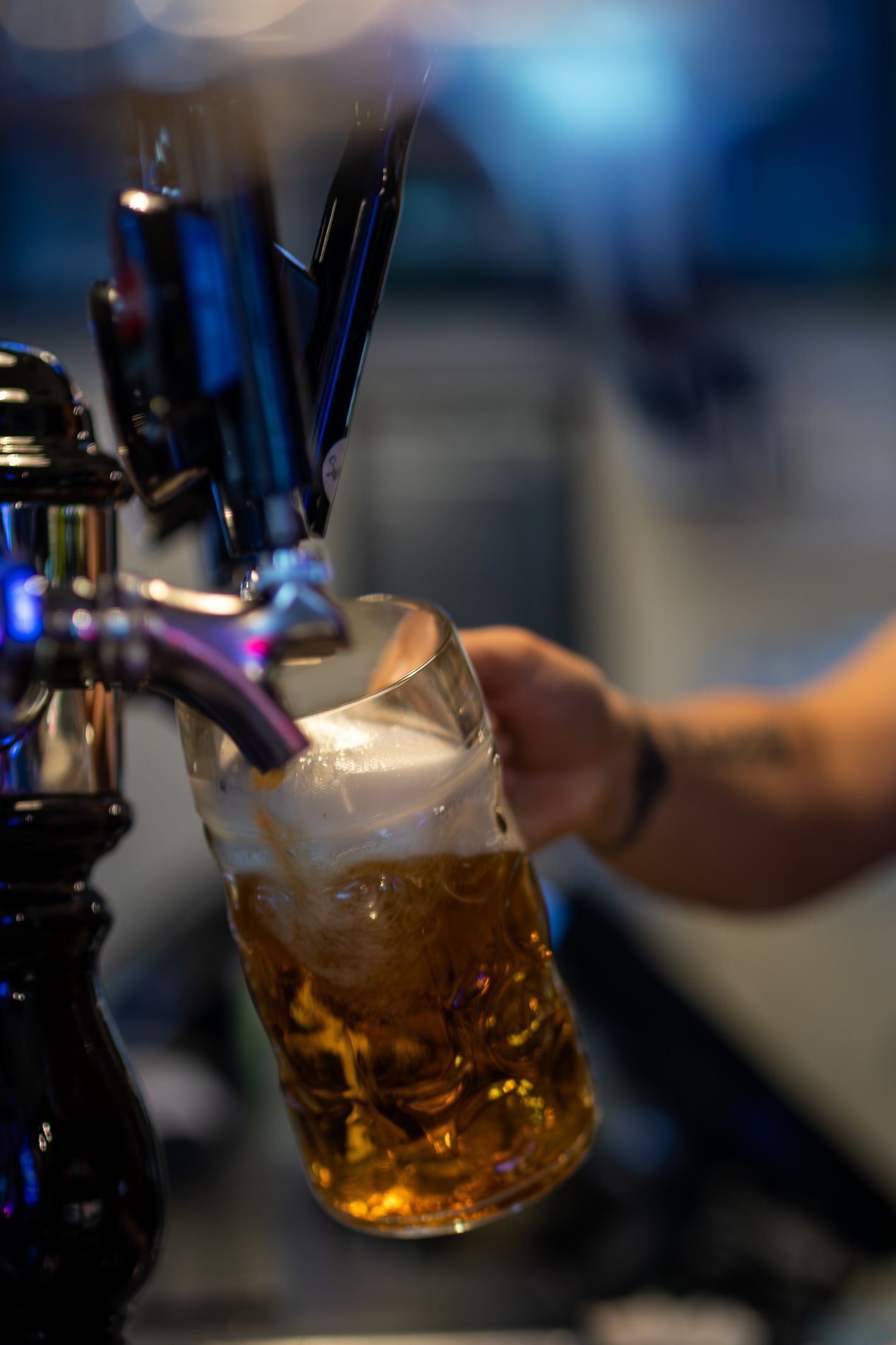 Golden beer being dispensed from draft tap with frothy head forming in glass.