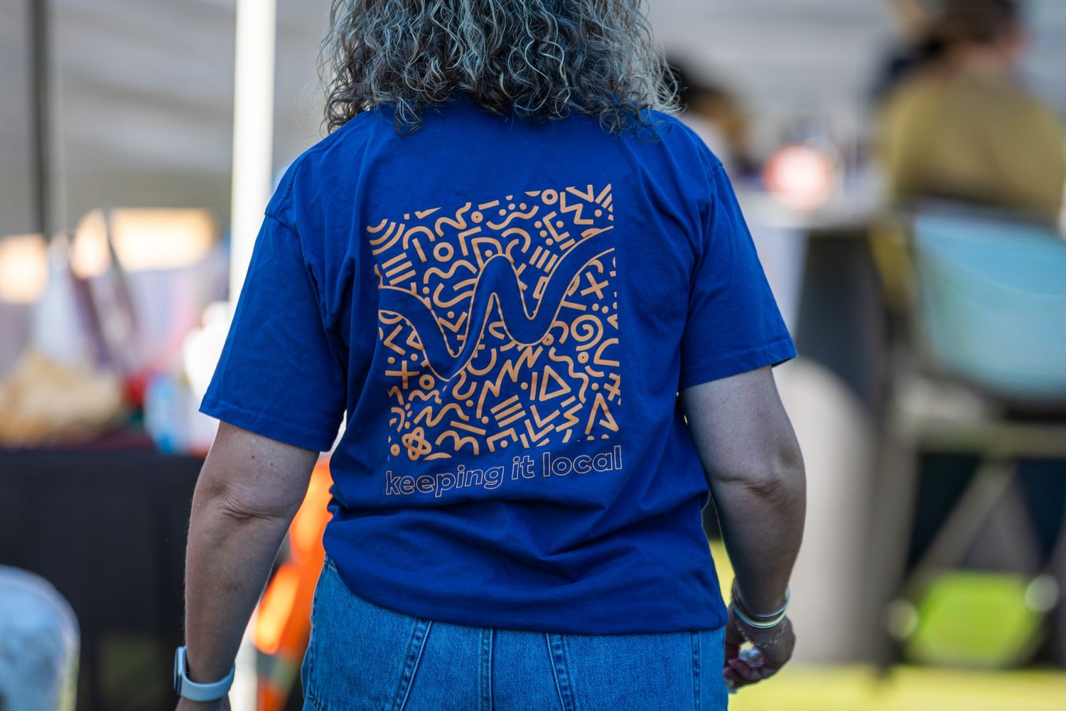 Blue t-shirts with matching abstract pattern designs at an outdoor gathering.