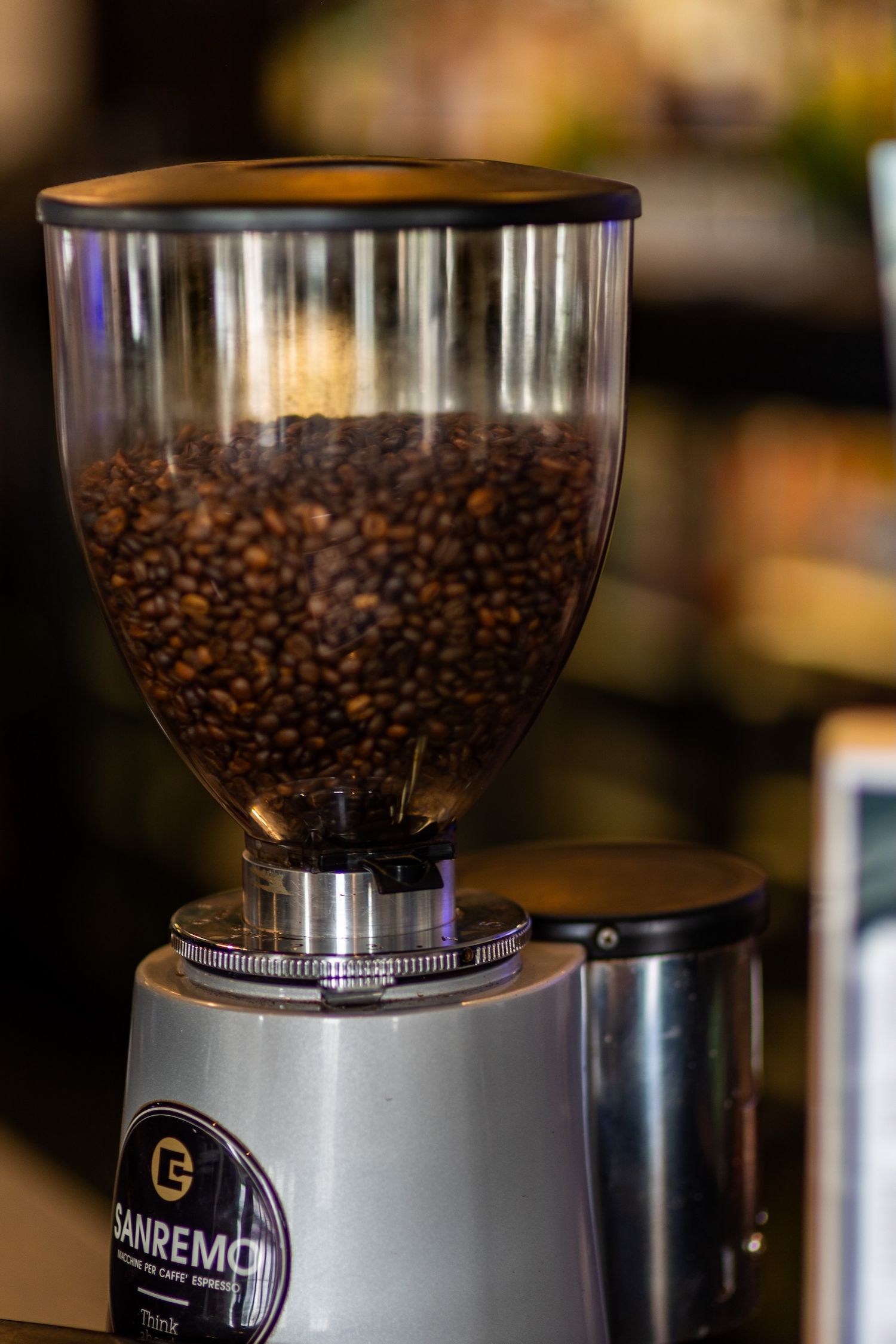 Coffee grinder filled with fresh roasted coffee beans in close-up view.