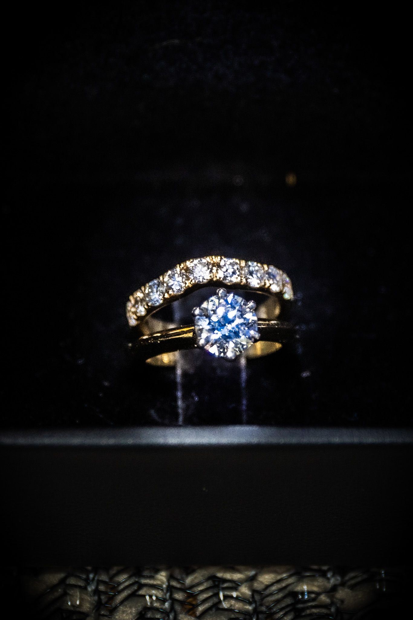Gold diamond engagement ring and wedding band set displayed on dark background, showcasing sparkling round-cut diamonds.