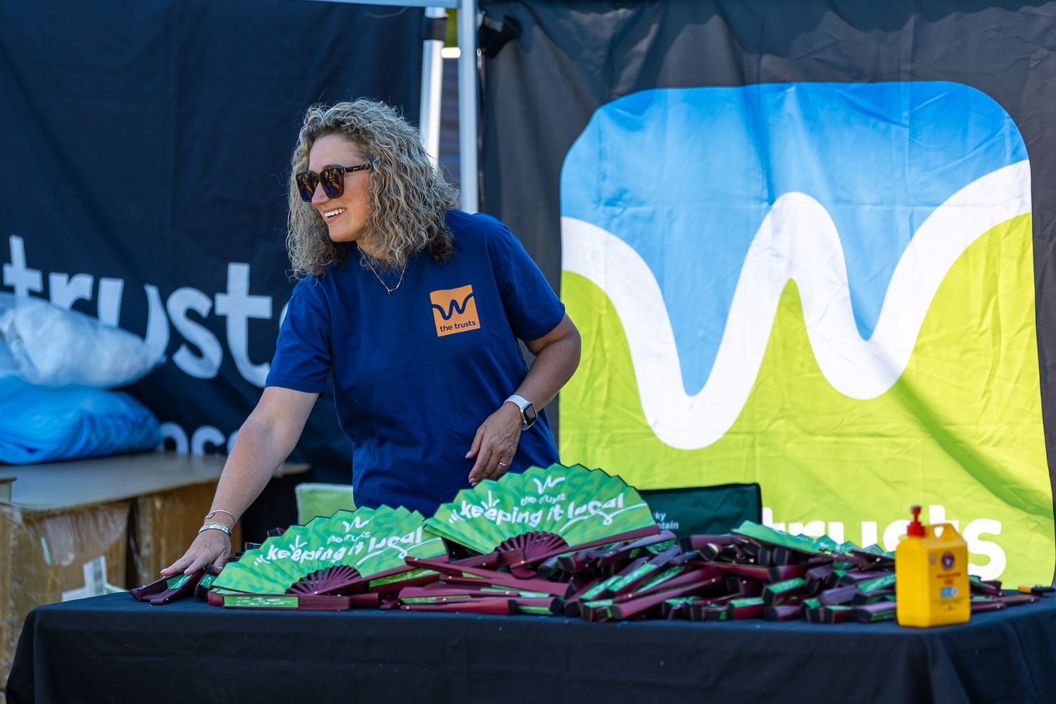 Event staff in blue shirts working behind tables at outdoor venue.