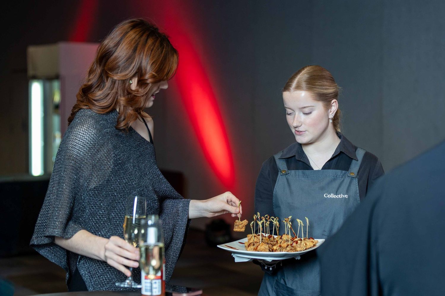 Service staff offering appetizers during an upscale corporate event.