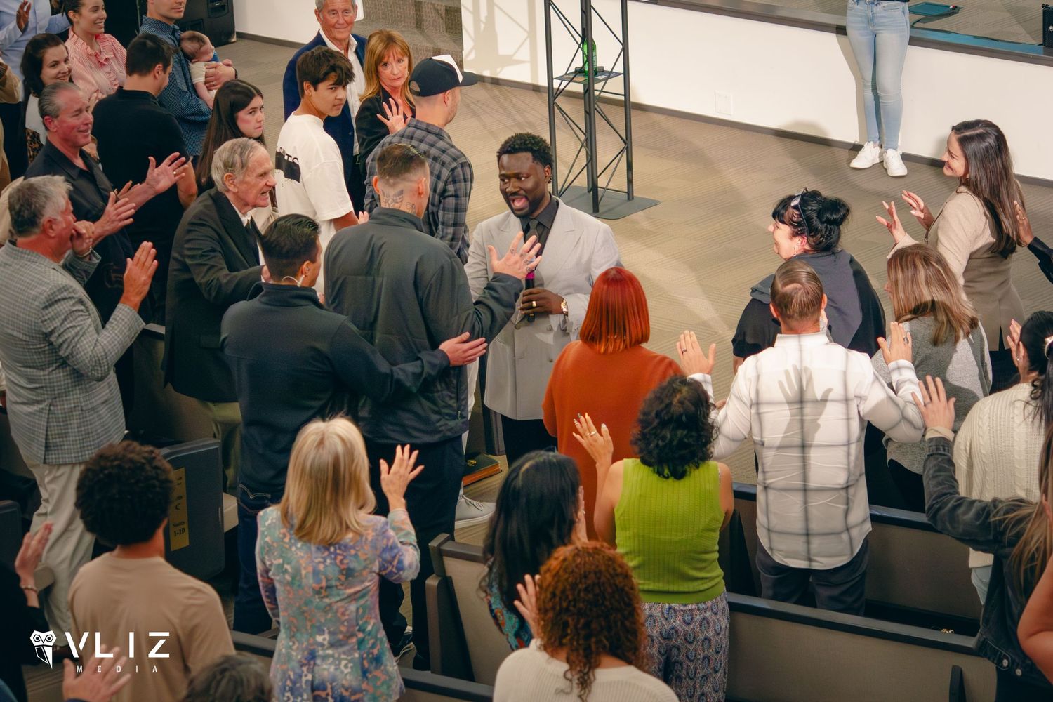 Diverse group of people applauding and celebrating together in a bright modern event space.