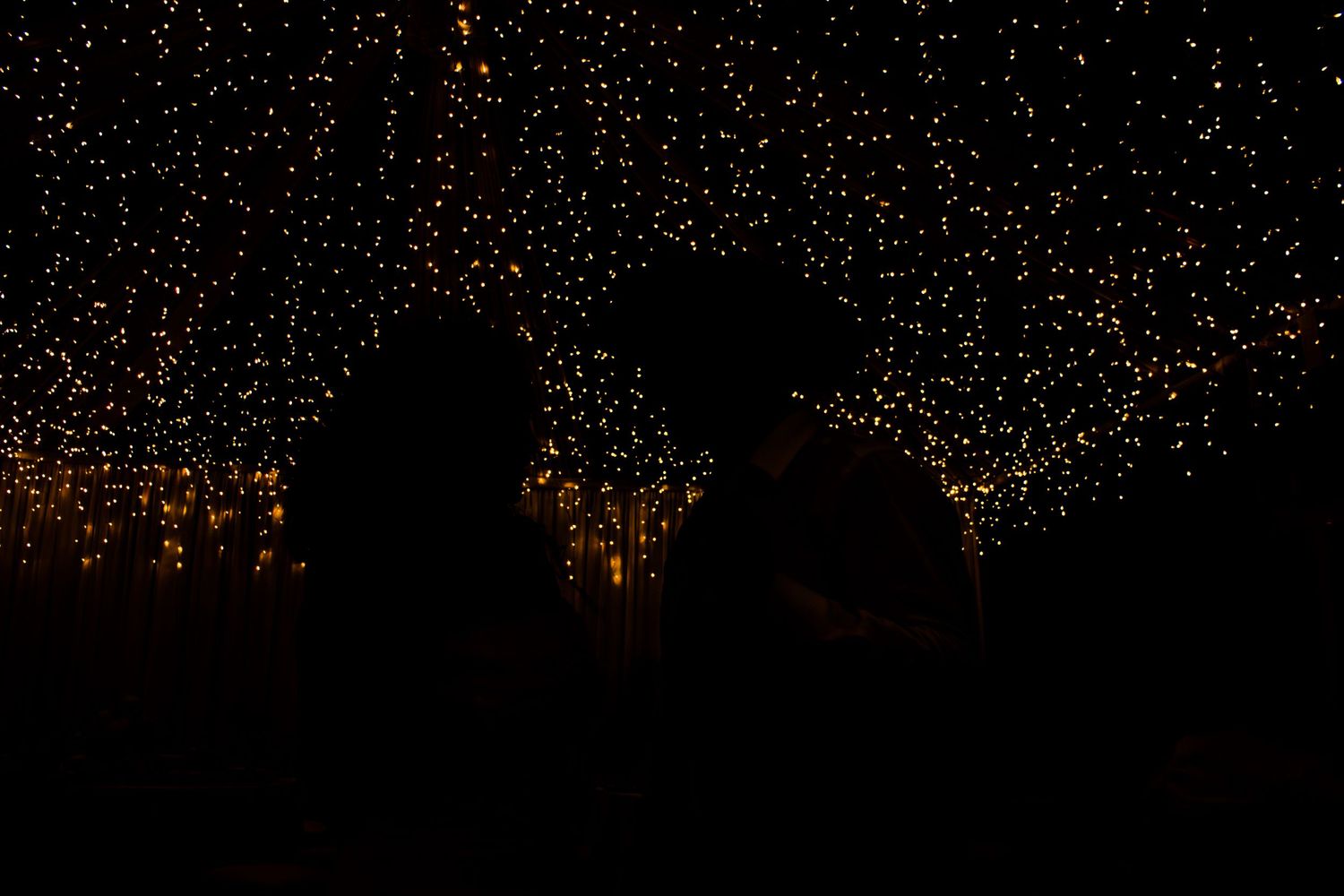 Silhouettes of a couple against a backdrop of twinkling fairy lights.