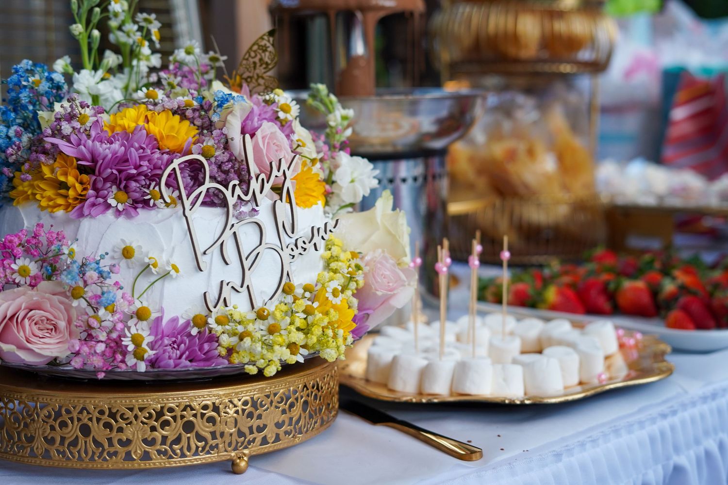 Colorful floral cake display with baby shower desserts and treats.