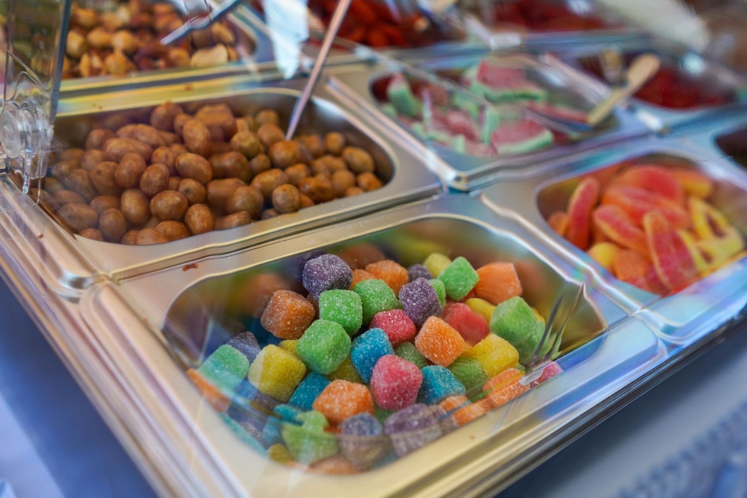Colorful assortment of candies and desserts displayed in serving trays at a party.