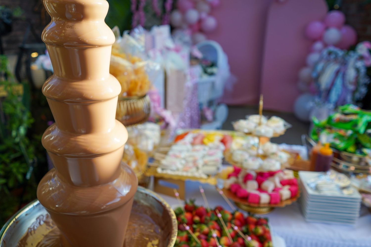 Elegant chocolate fountain display with fresh fruits and desserts at an upscale catering event.