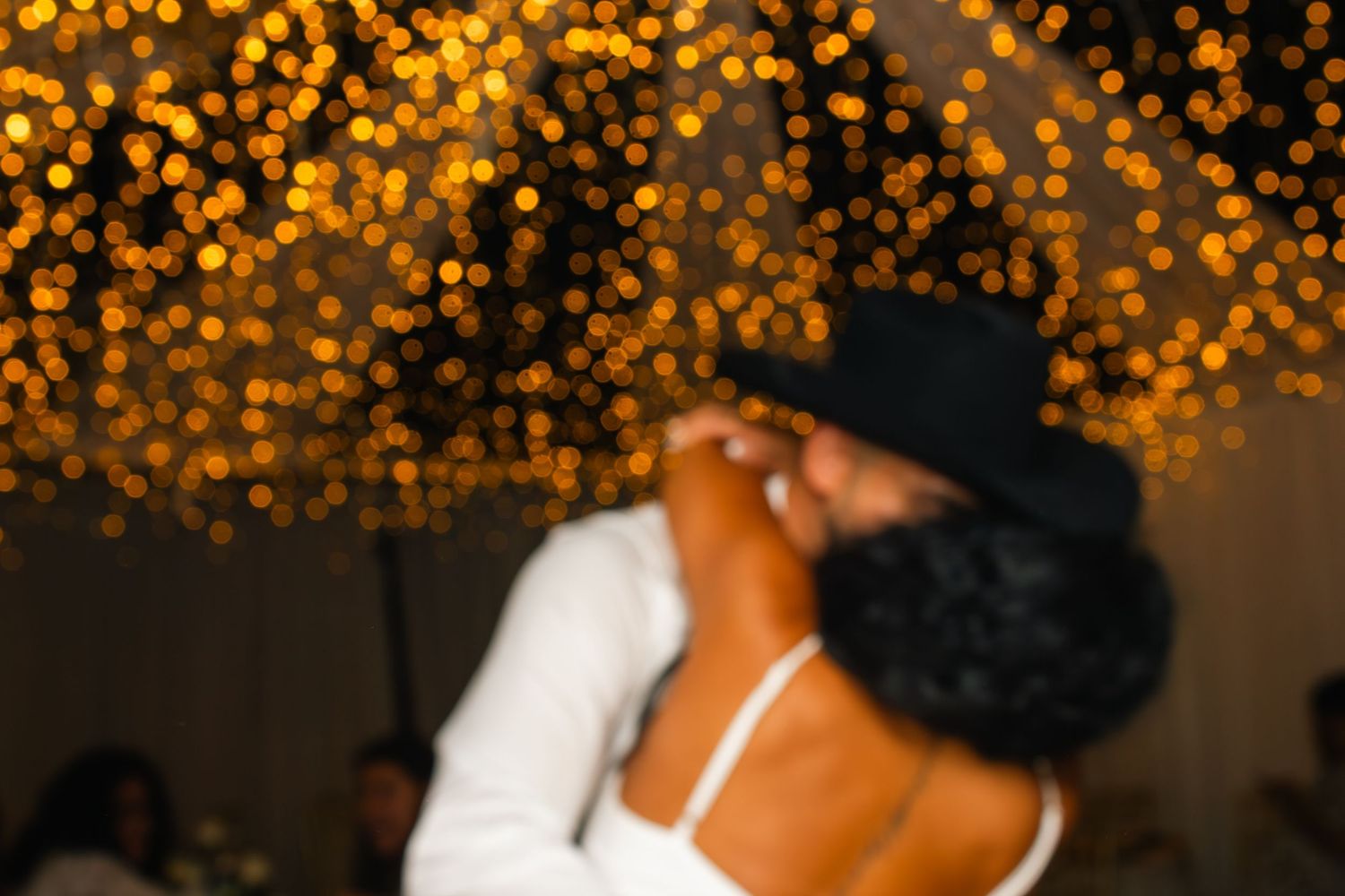 Intimate dance moment captured against a backdrop of golden bokeh lights.
