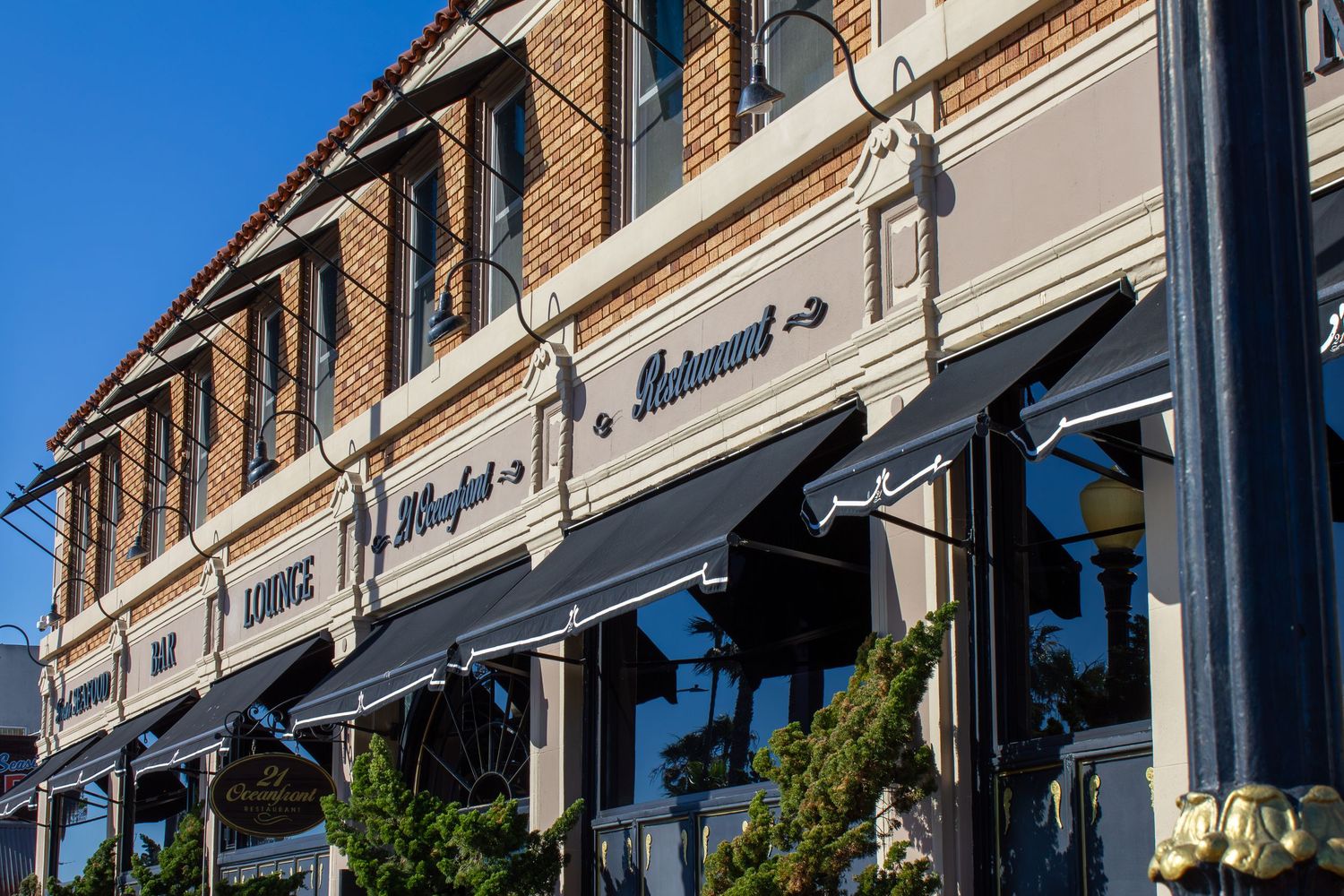 Historic brick restaurant building with elegant striped awnings and decorative facade on a sunny day.