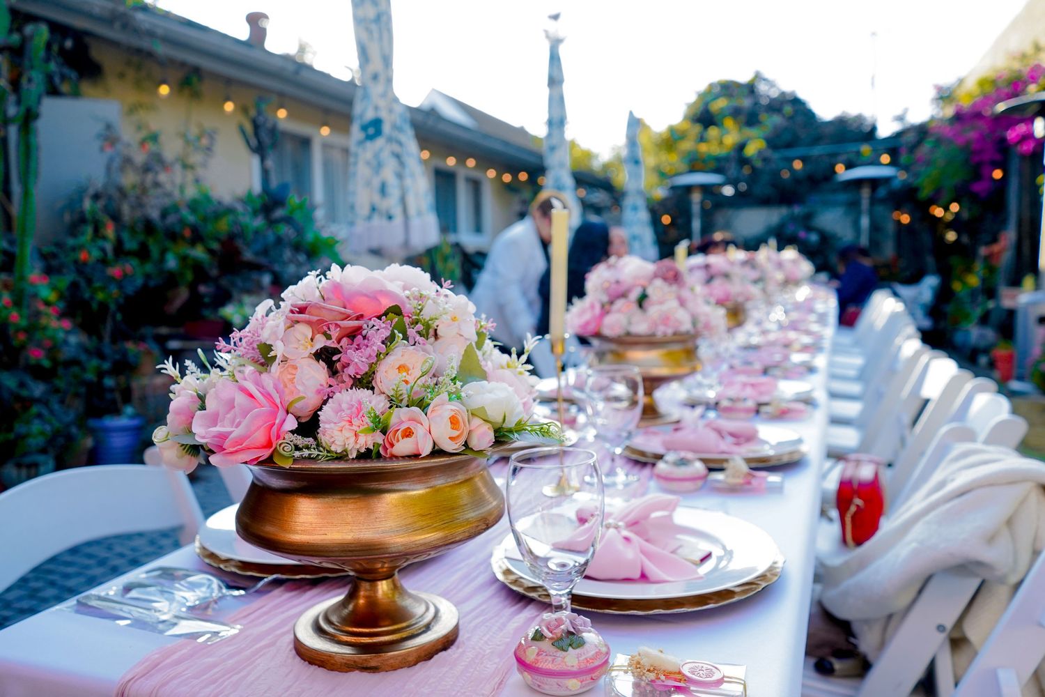 Outdoor wedding reception setup with elegant table settings and floral arrangements.